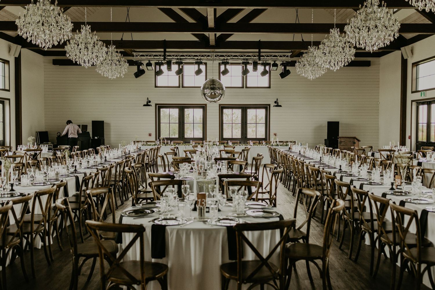 An elegant wedding reception venue with crystal chandeliers and tables set for dinner in a spacious ballroom.