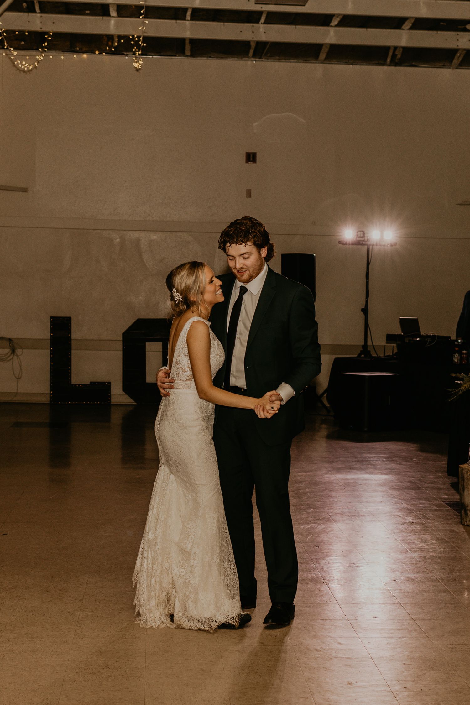 Couple dancing in an intimate moment on dimly lit reception dance floor.