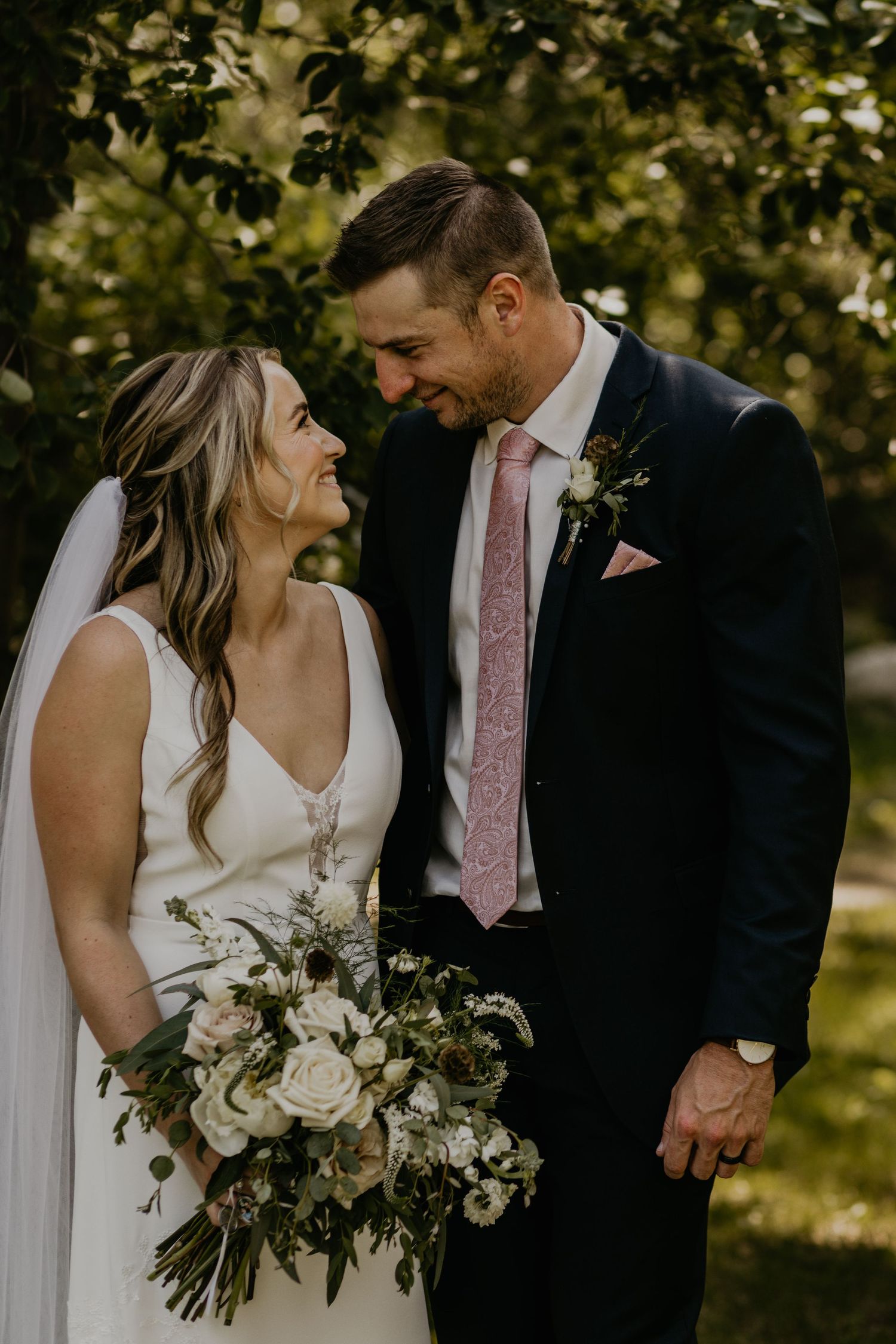 Intimate moment between newlyweds sharing a loving glance in a garden setting.