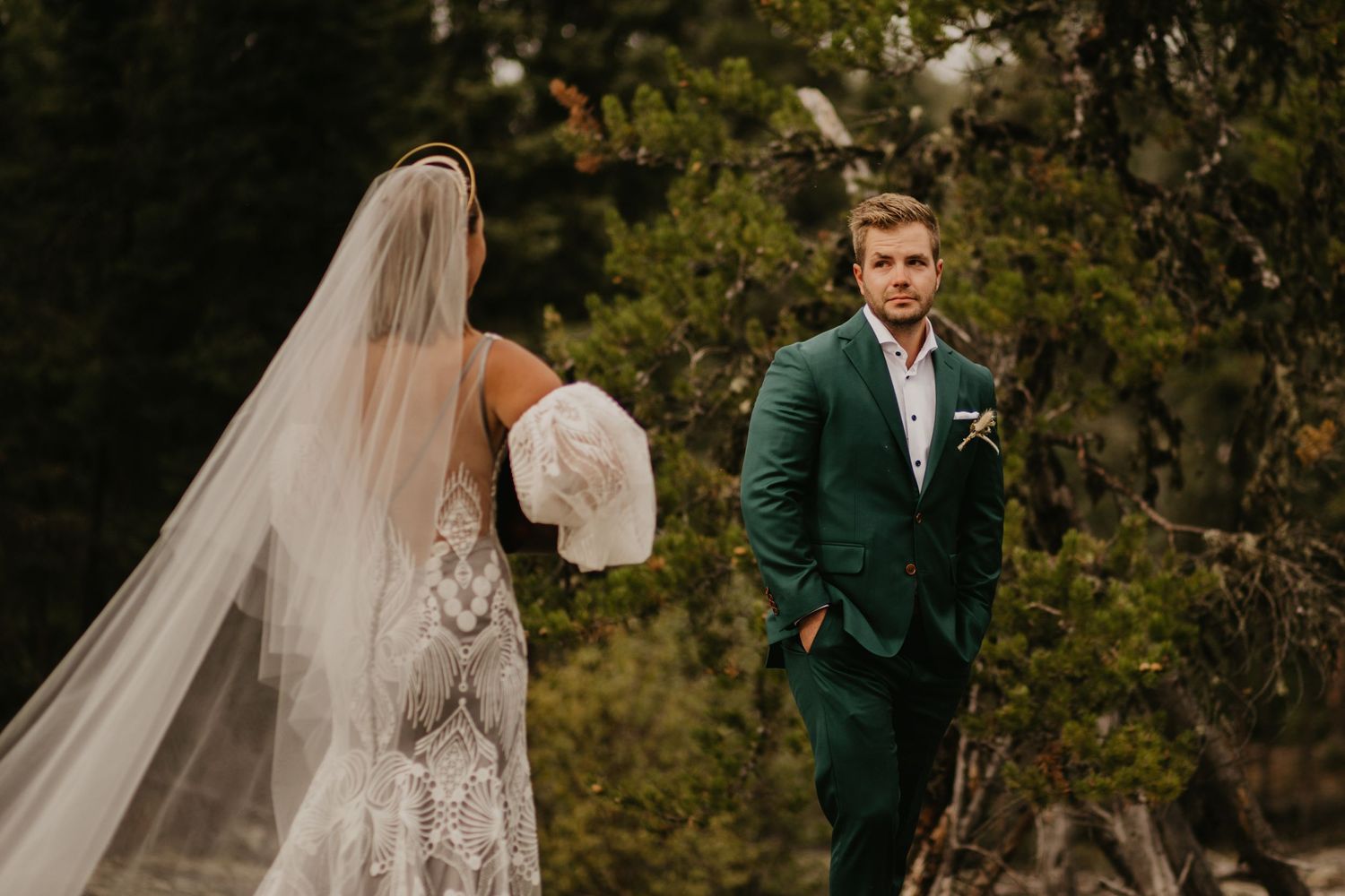 Elegant outdoor wedding photoshoot with dramatic forest backdrop and emerald green suit.