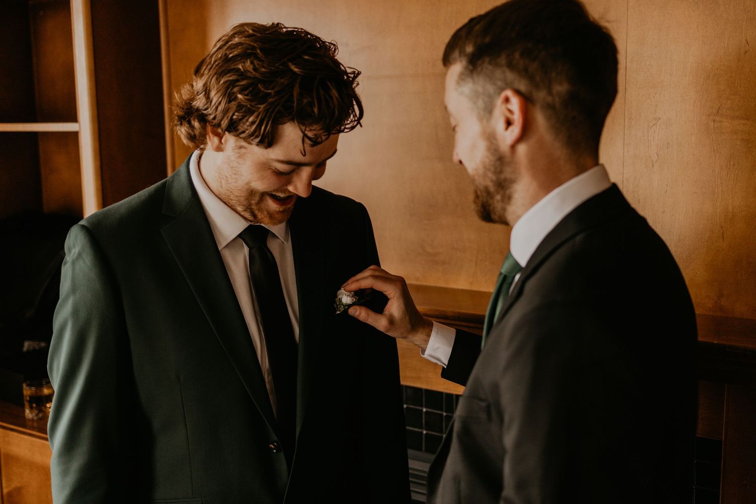 Two people in suits having a conversation in warm indoor lighting.