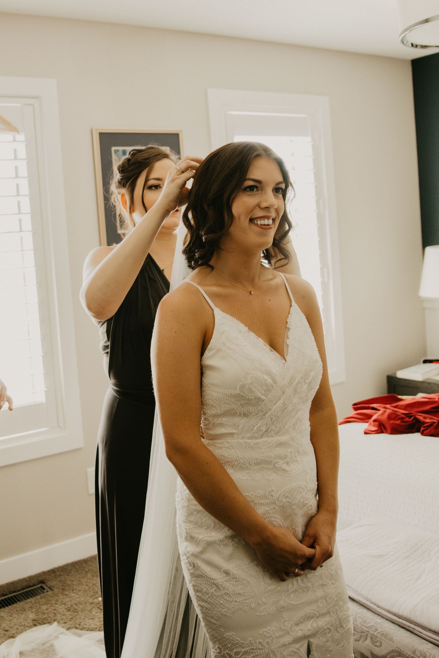 Final preparations being made with a white wedding dress in a bright sunlit room.