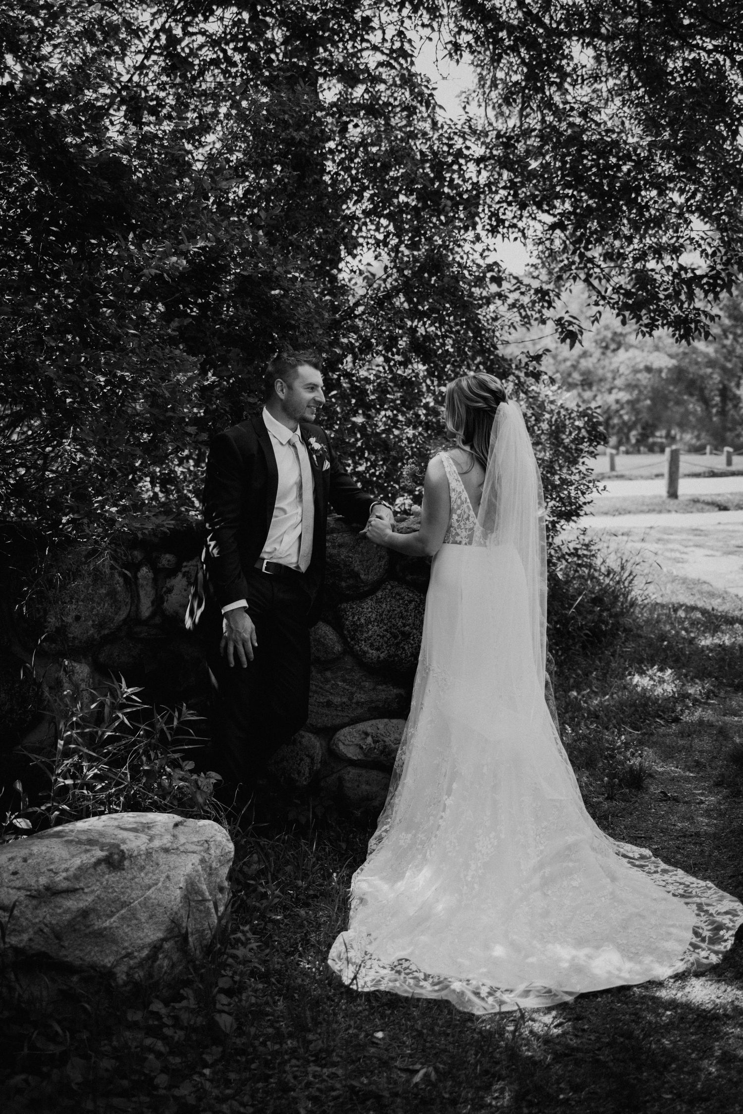 Black and white wedding portrait showcasing bride's elegant lace train dress.