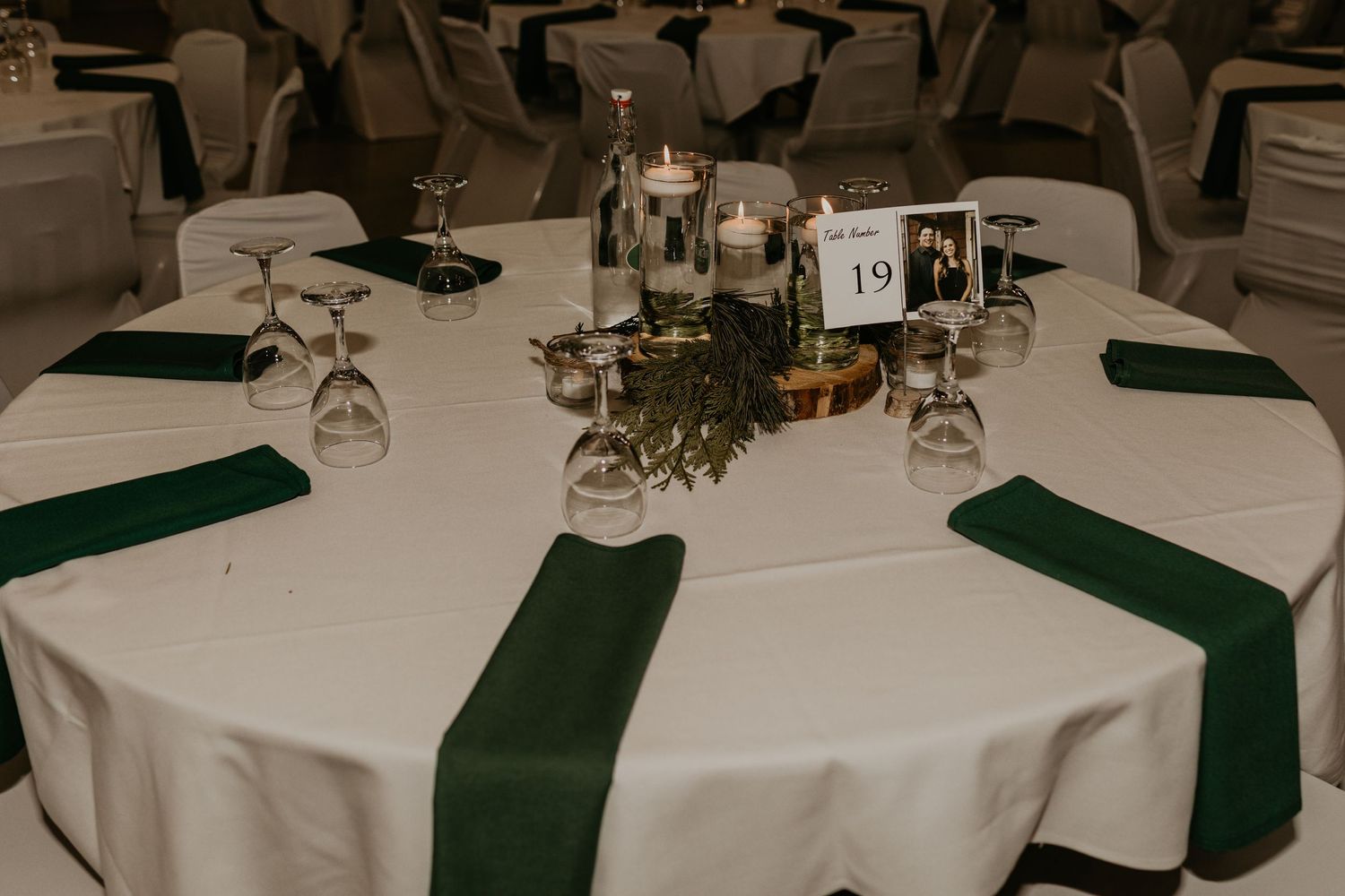 Wedding reception table set with white linens, green napkins, and elegant centerpiece decorations.