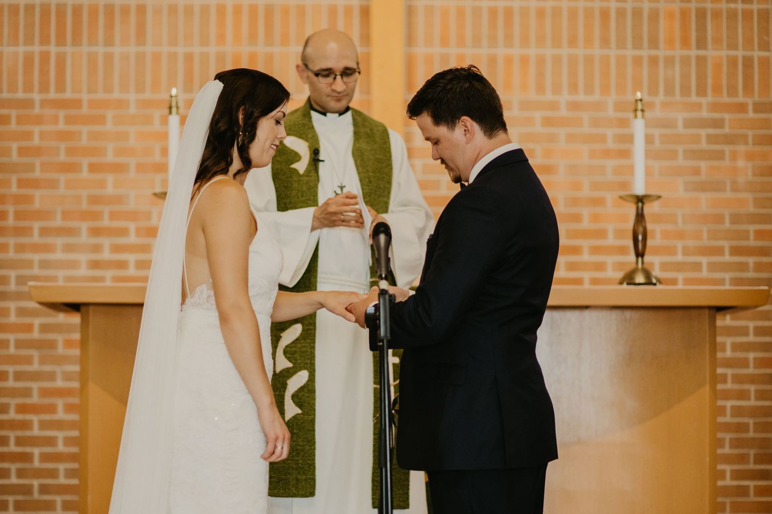 A wedding ceremony taking place in a brick church with the officiant leading the service.