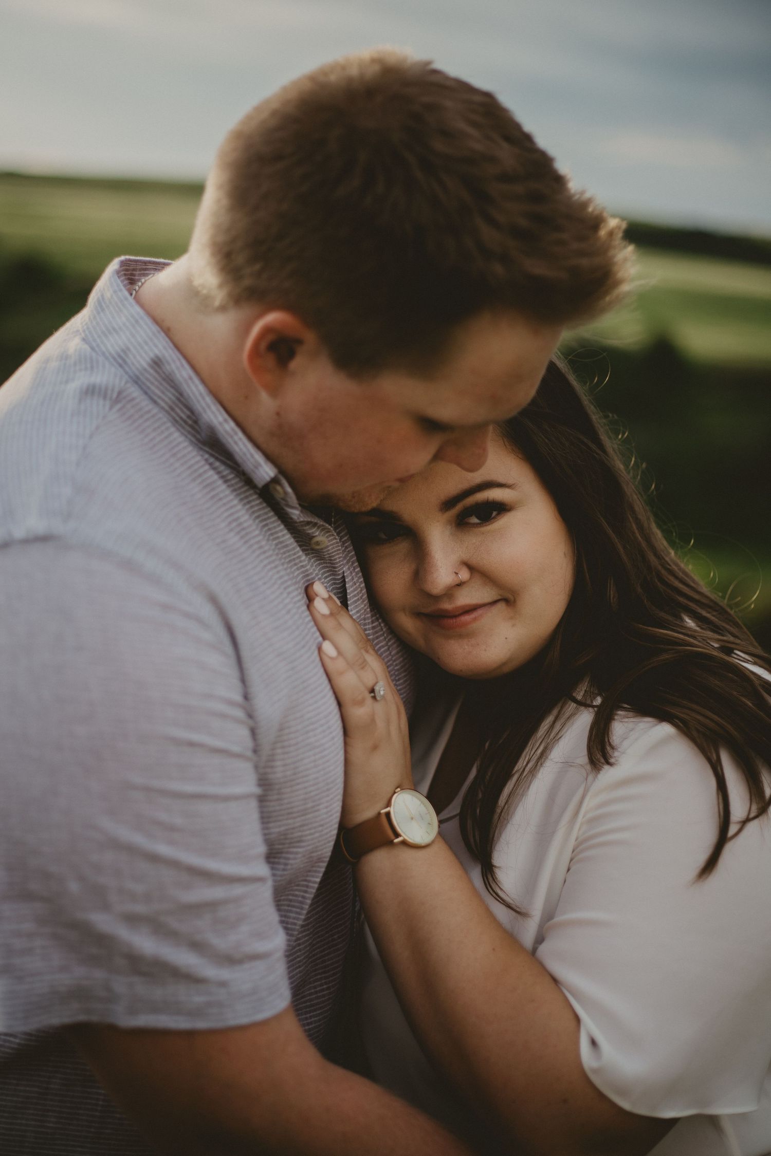 An intimate outdoor portrait of a romantic couple sharing a tender moment at sunset.