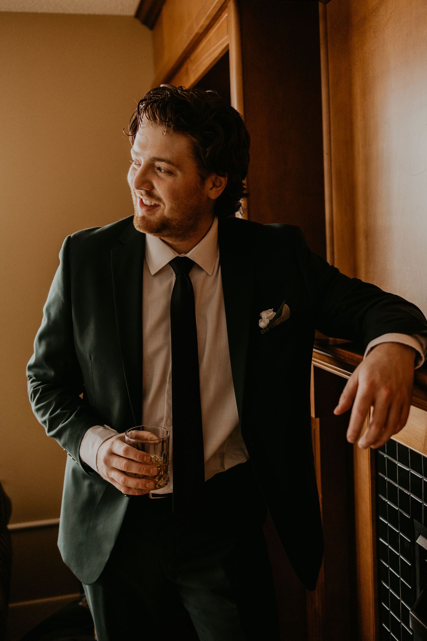 Groomsmen in dark suits checking their phones while getting ready.