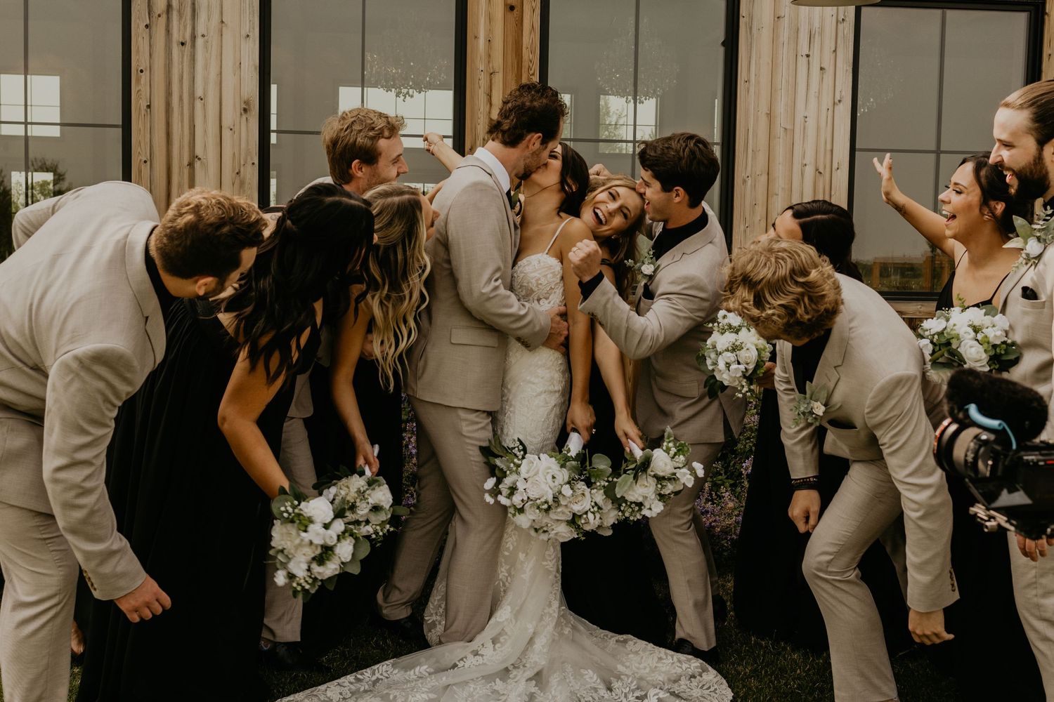 Wedding party creates a dynamic motion blur effect in black and white outside a rustic venue.