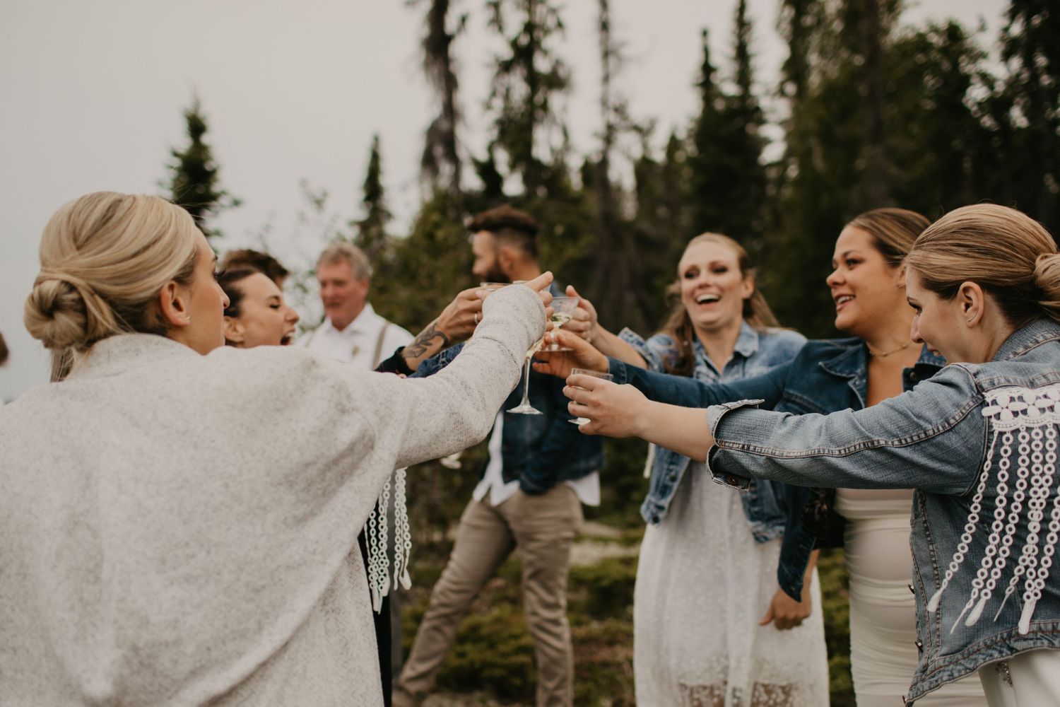 Wedding party members toast together outdoors in a circle formation.