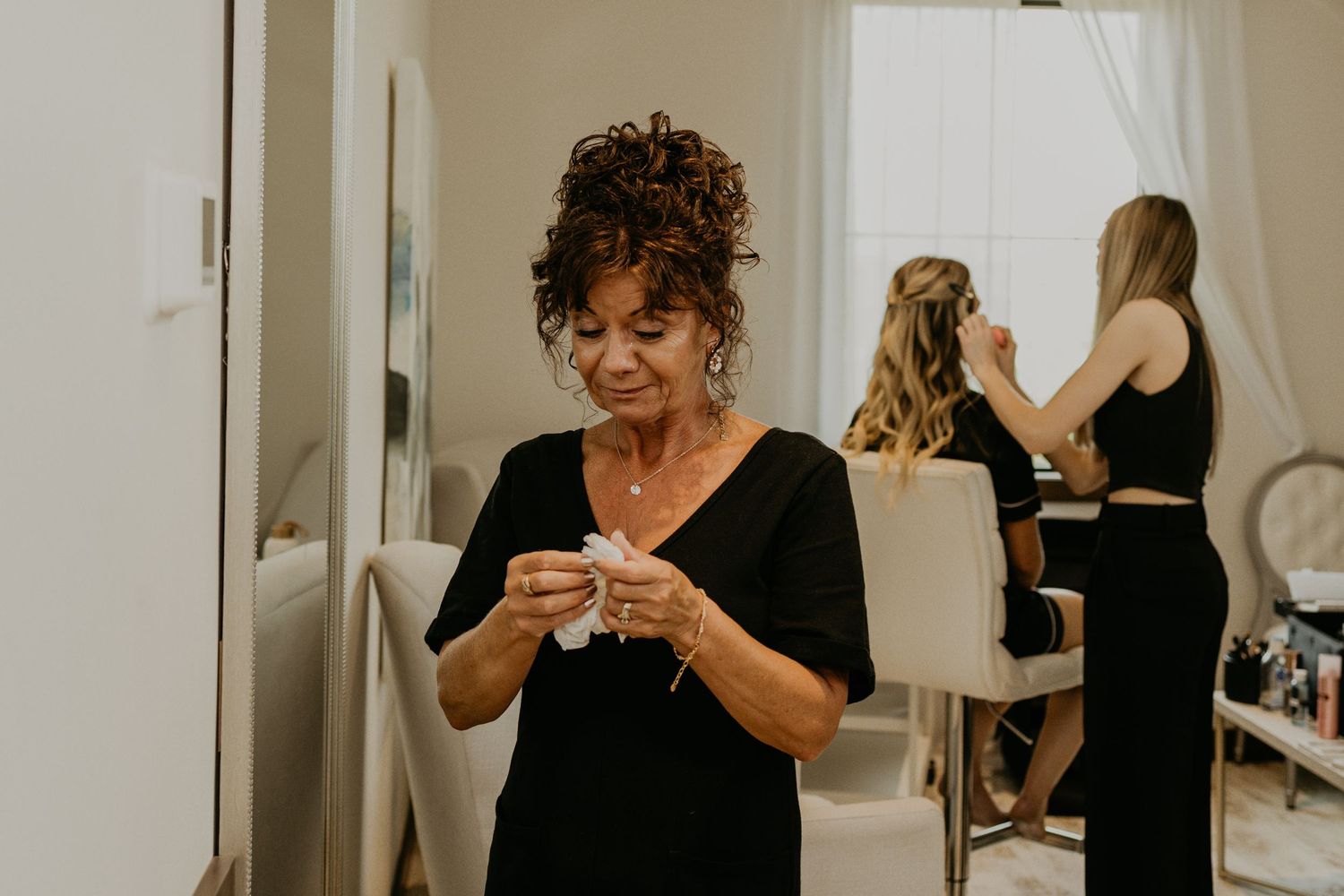 Wedding preparation scene with people getting ready in a bright dressing room.