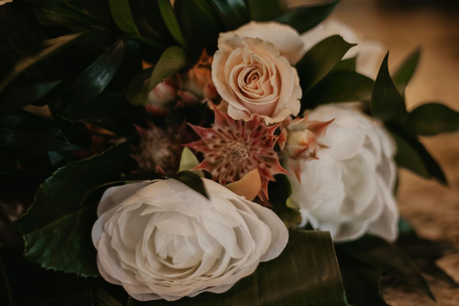 Close-up of cream roses and foliage in romantic wedding floral arrangement.