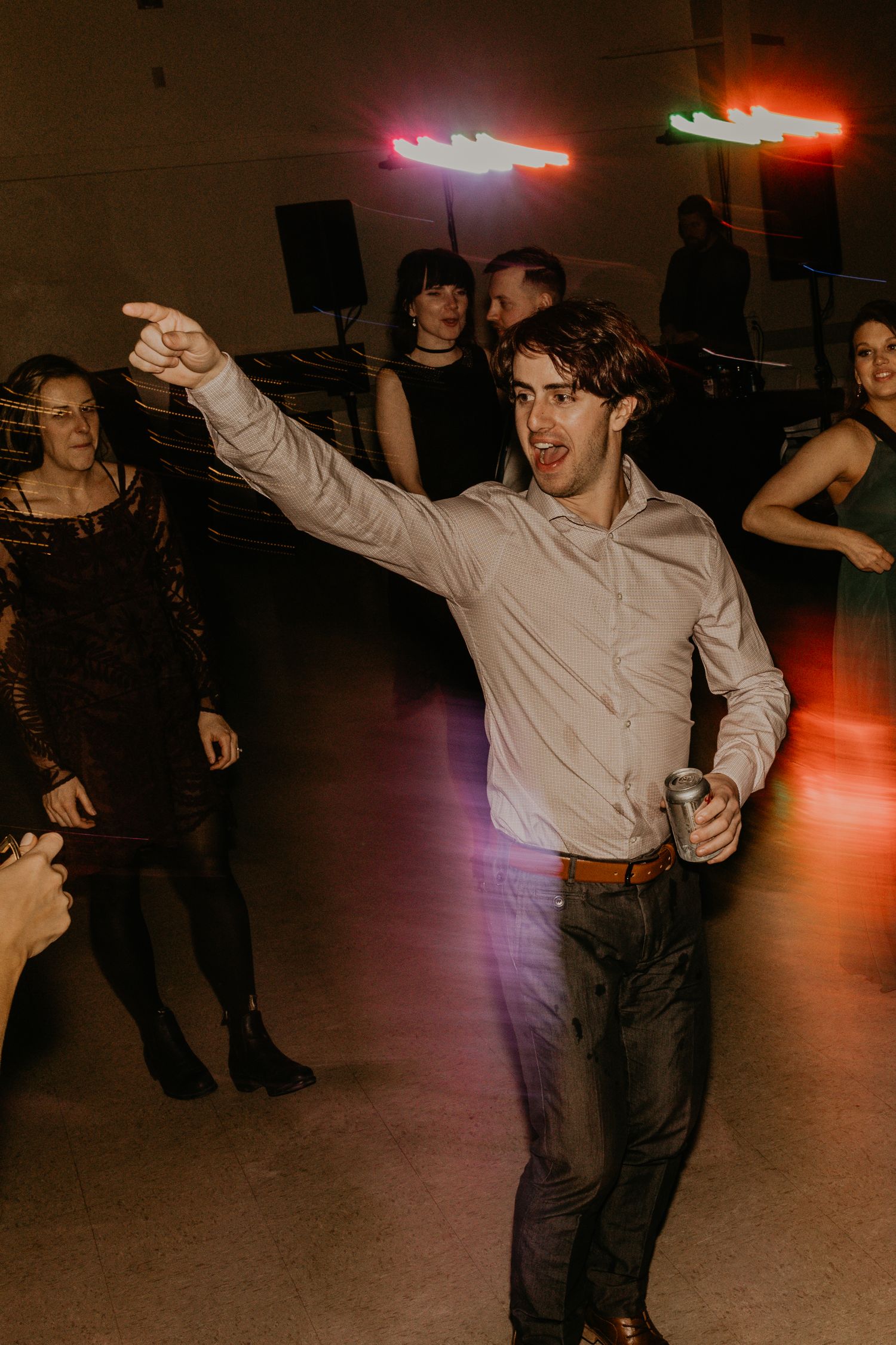 Party guest enthusiastically dancing on the dance floor under colorful lighting.