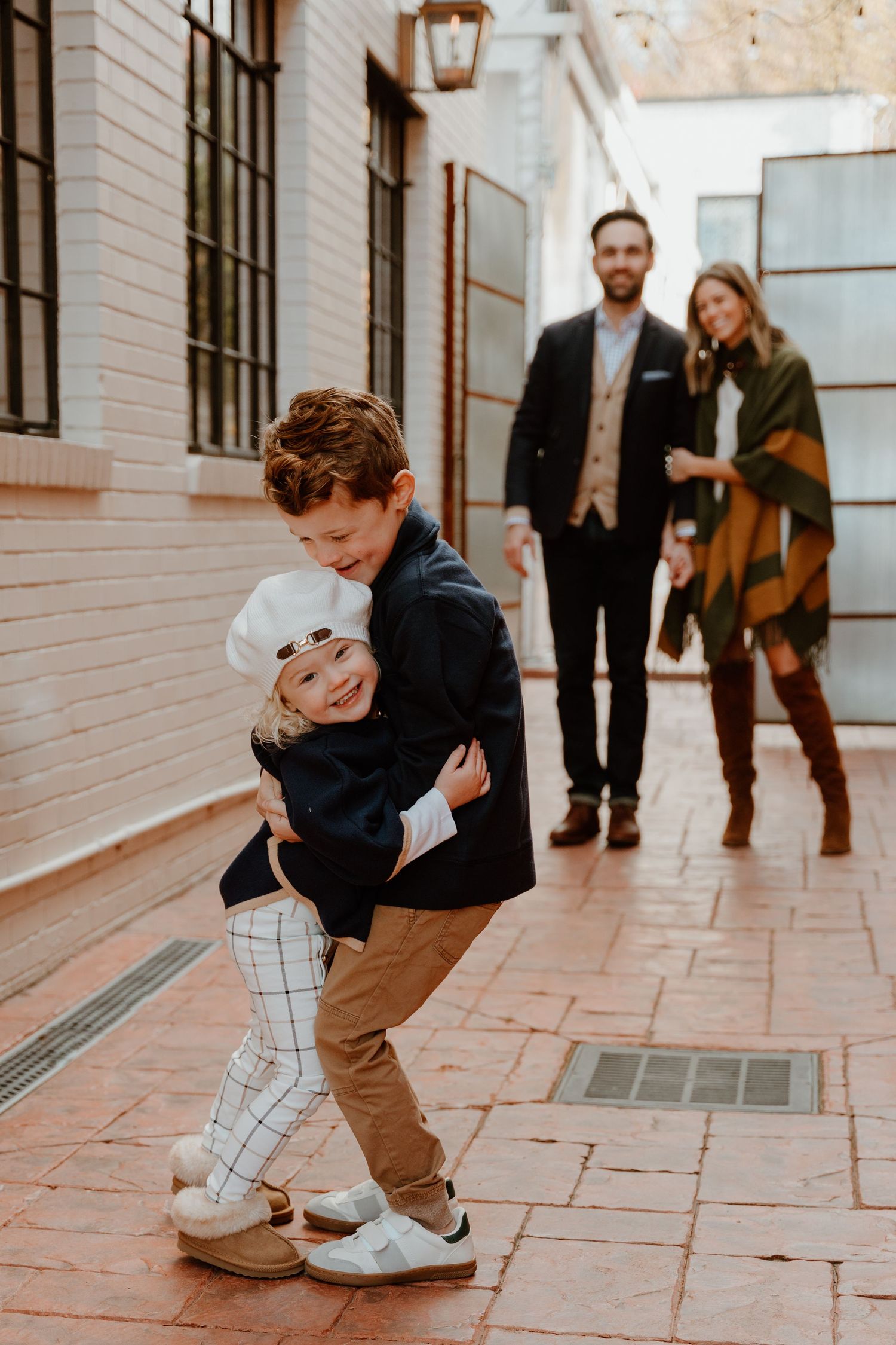 A sweet moment captured in a sequence showing a couple embracing and dancing playfully in a brick corridor.