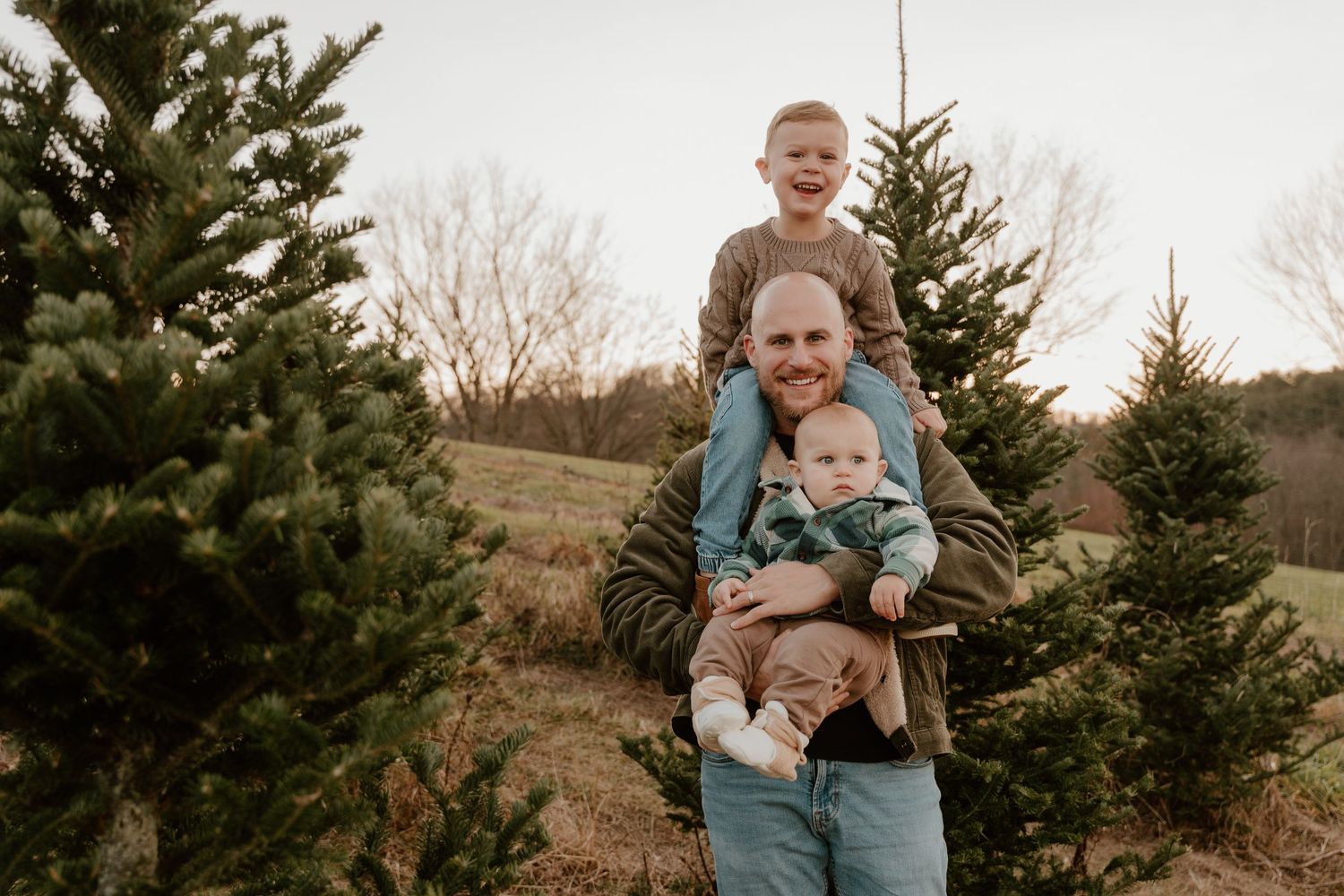 A joyful moment captured at a Christmas tree farm with evergreen trees in the background during winter.