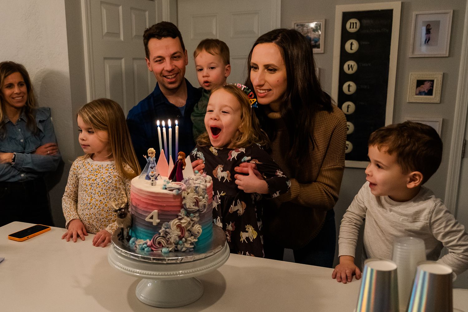 Birthday celebration scene with a decorated cake and lit candles being blown out at a family gathering.