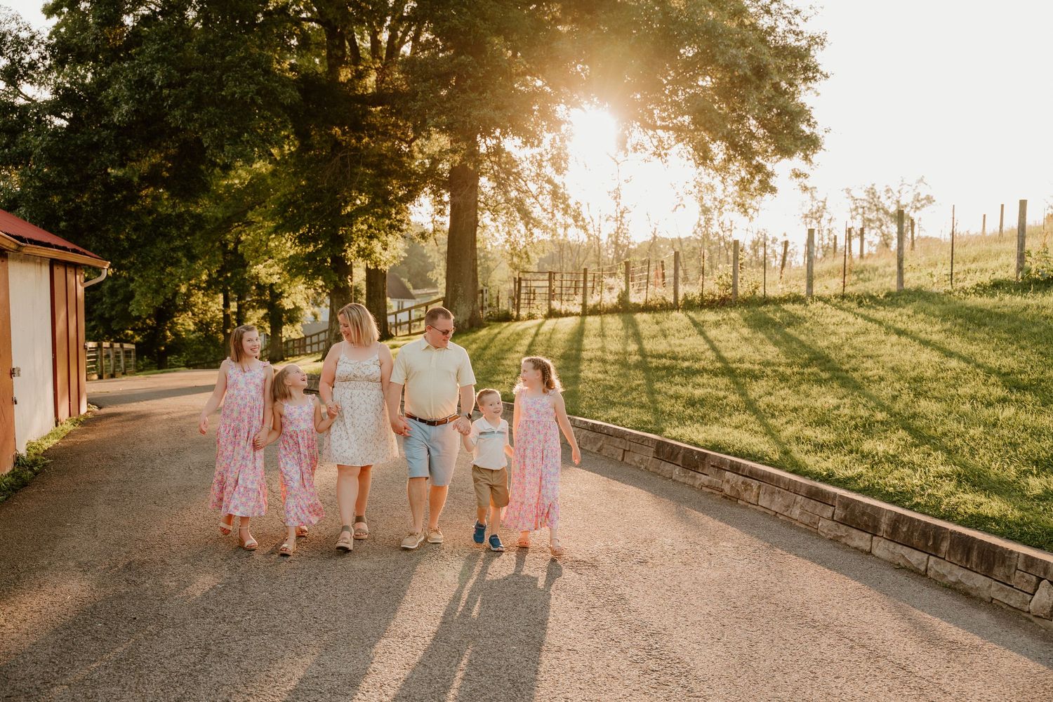 People walking along a scenic path at sunset with golden sunlight filtering through trees in the background.