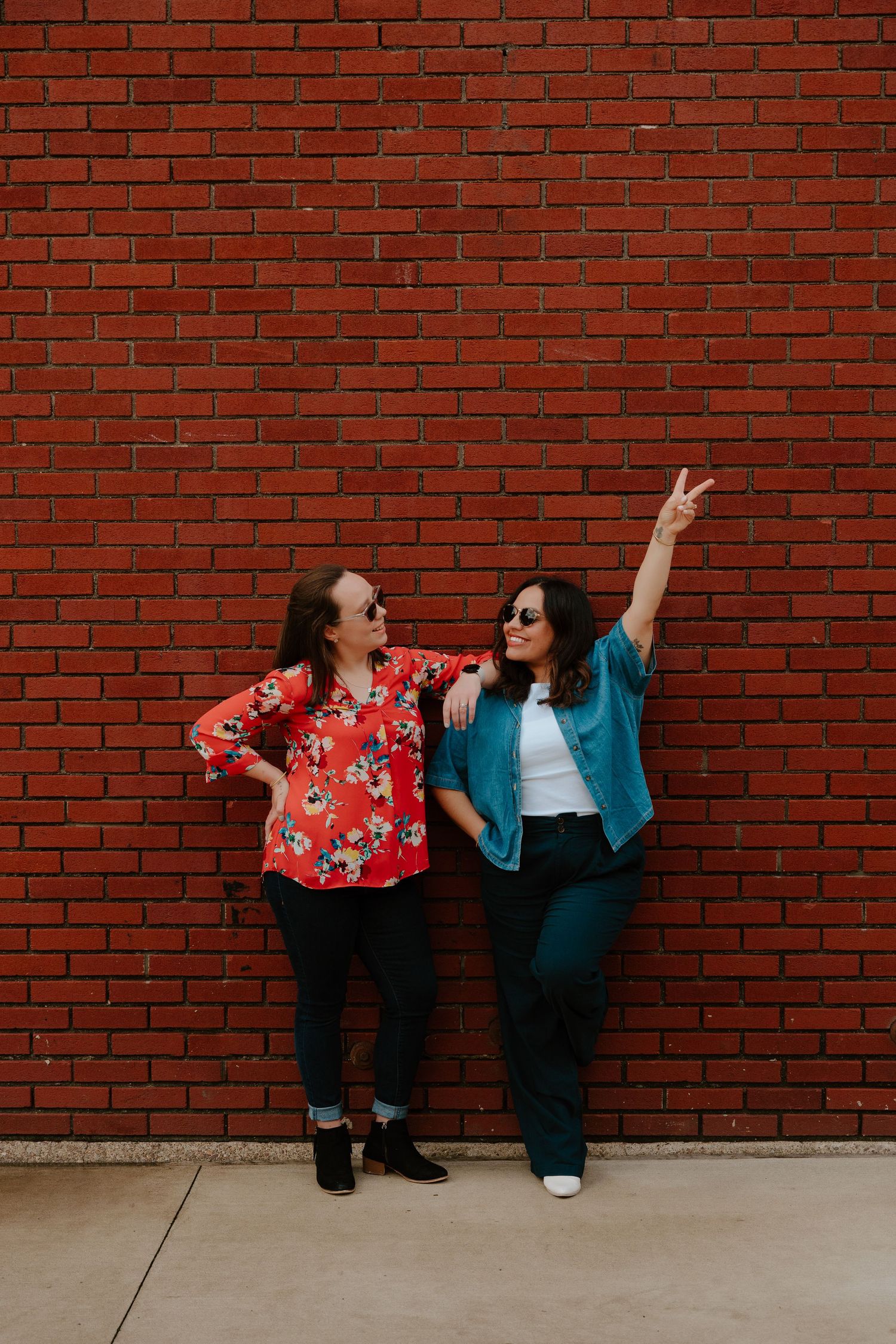Two friends in contrasting outfits pose playfully against a red brick wall in a progressive photo sequence.