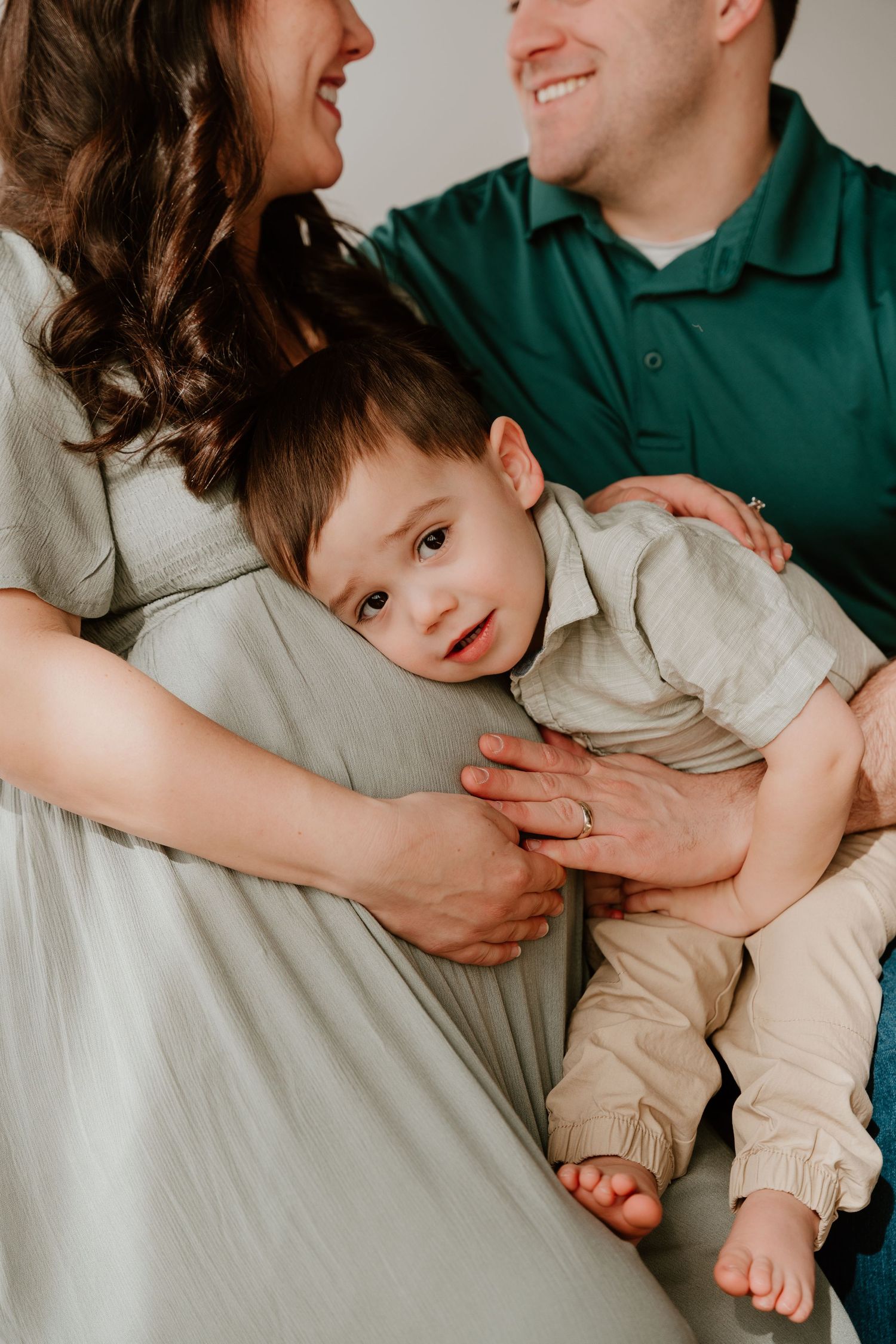 Series of candid family moments showing affectionate interactions while sitting against a white wall.