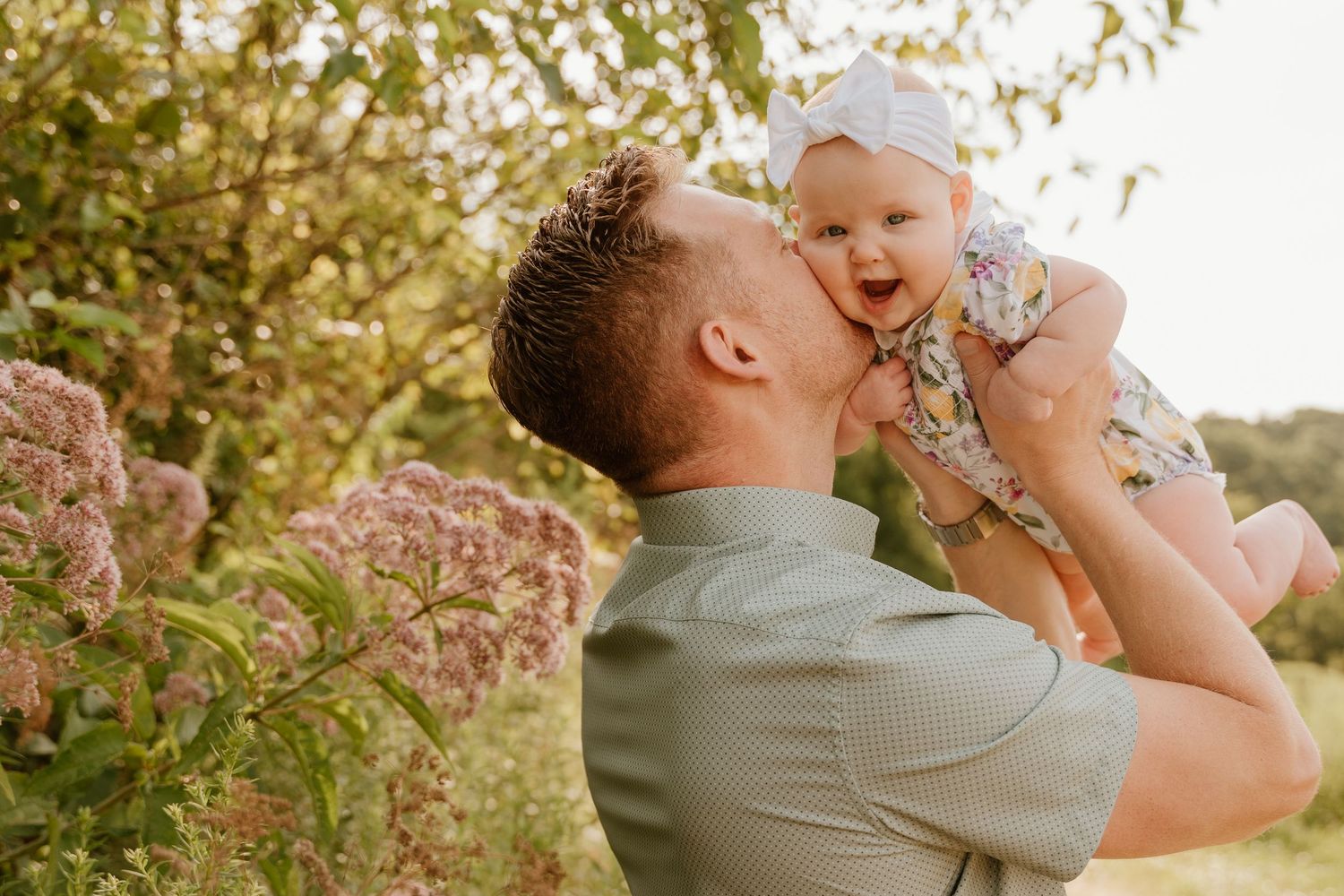 Family sharing joyful moments together in a golden-hour outdoor setting with blooming flowers.