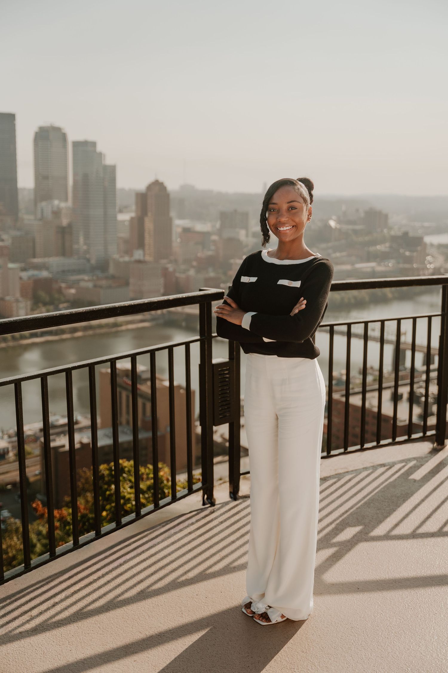 Professional stands confidently on an observation deck overlooking a cityscape at golden hour.