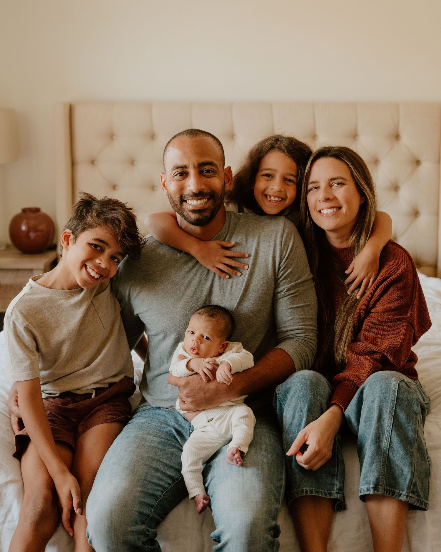 A heartwarming family portrait series showing tender moments on a beige couch in matching casual outfits.
