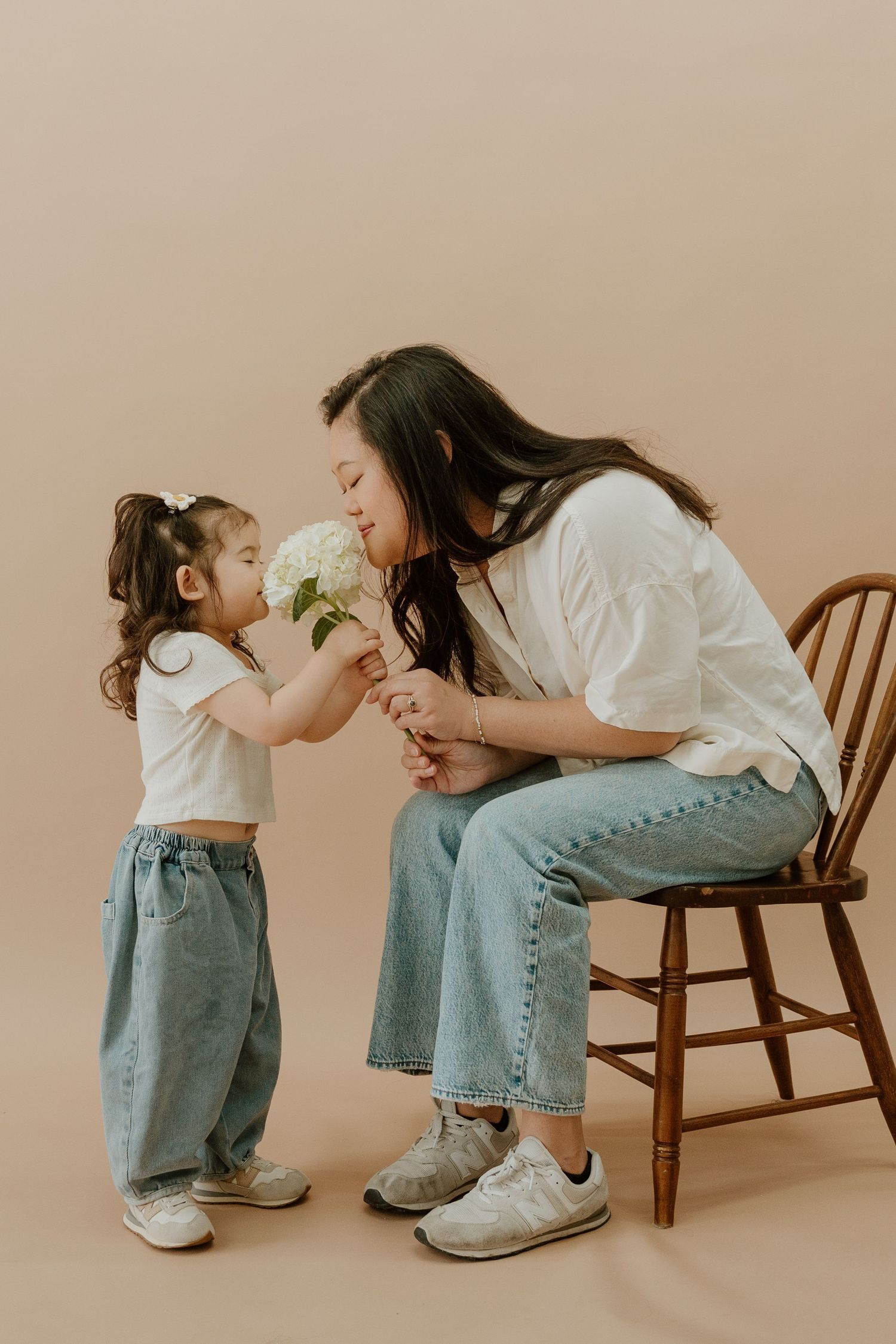 A heartwarming sequence of a parent and toddler sharing tender moments while sitting on a wooden chair in a studio setting.