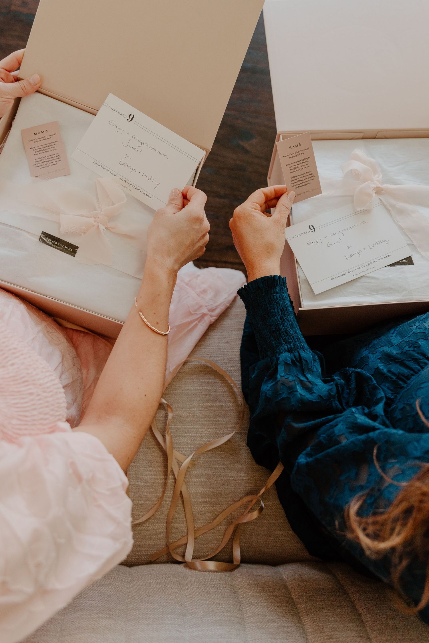 Two people in pink and navy blue clothing look through documents and papers together on a couch.