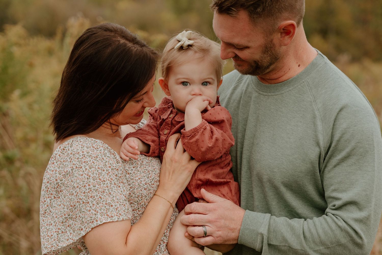 A family shares tender moments together during an outdoor autumn photoshoot in warm earth tones.