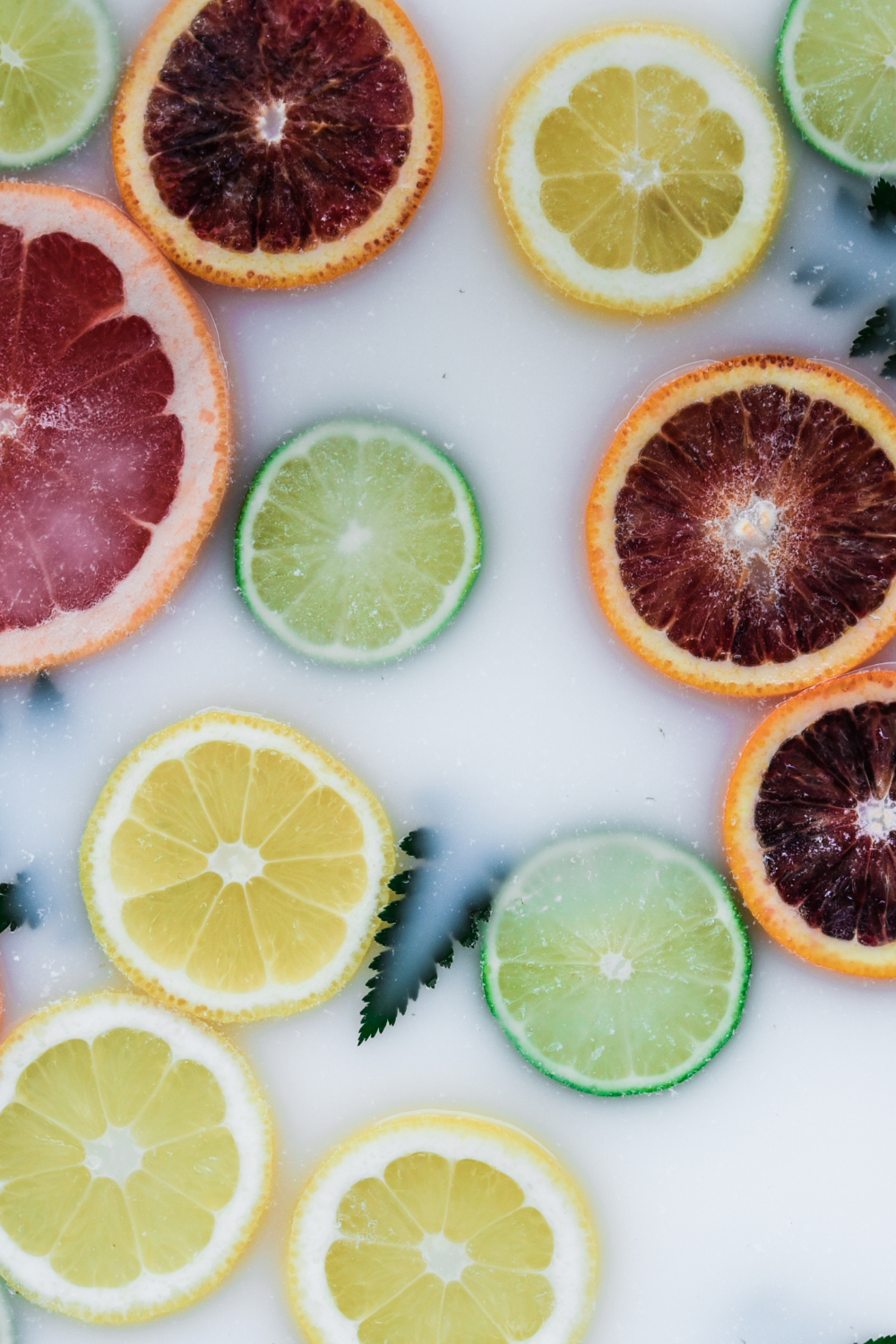 Vibrant citrus slices including blood orange, lemon, and lime arranged on white background.
