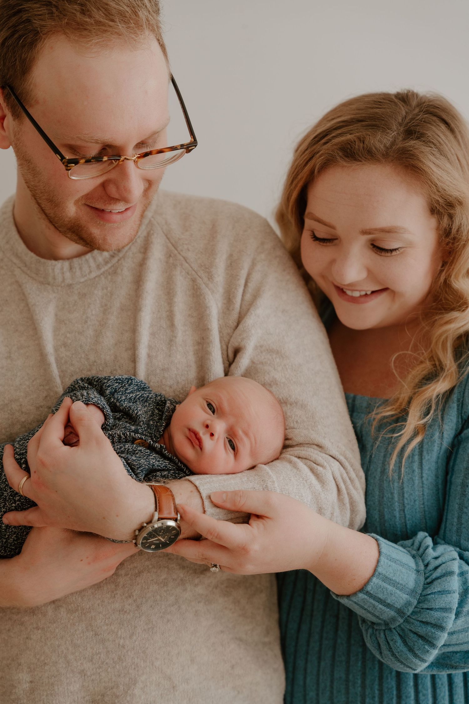 A series of intimate family photos showing tender moments between parents and baby in soft neutral tones.