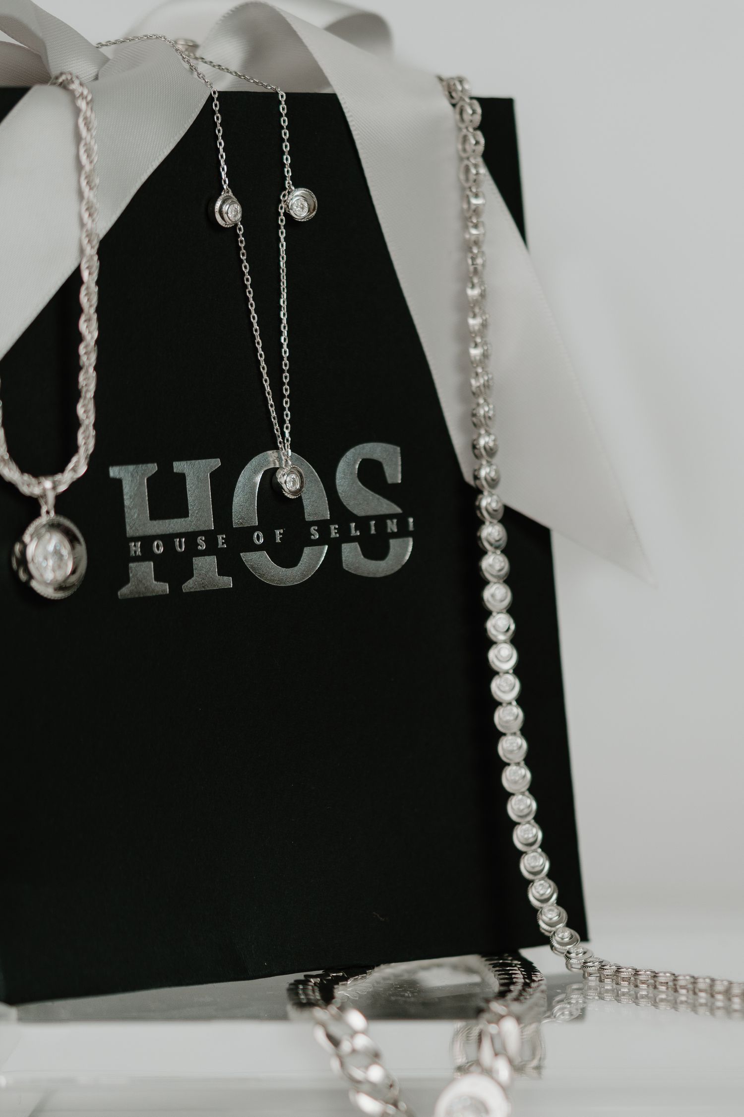 A series of pearl necklaces and jewelry pieces displayed against a black and white background.