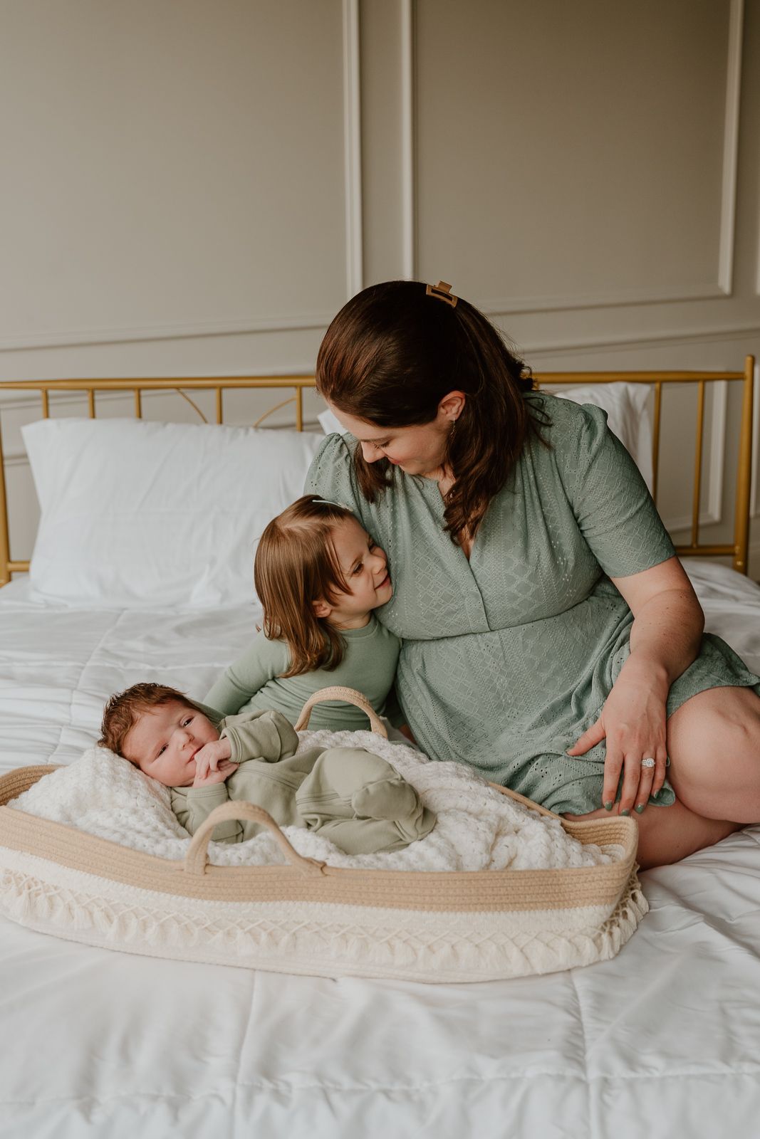 A tender family moment captured on a bed with young children and parent sharing loving interactions.