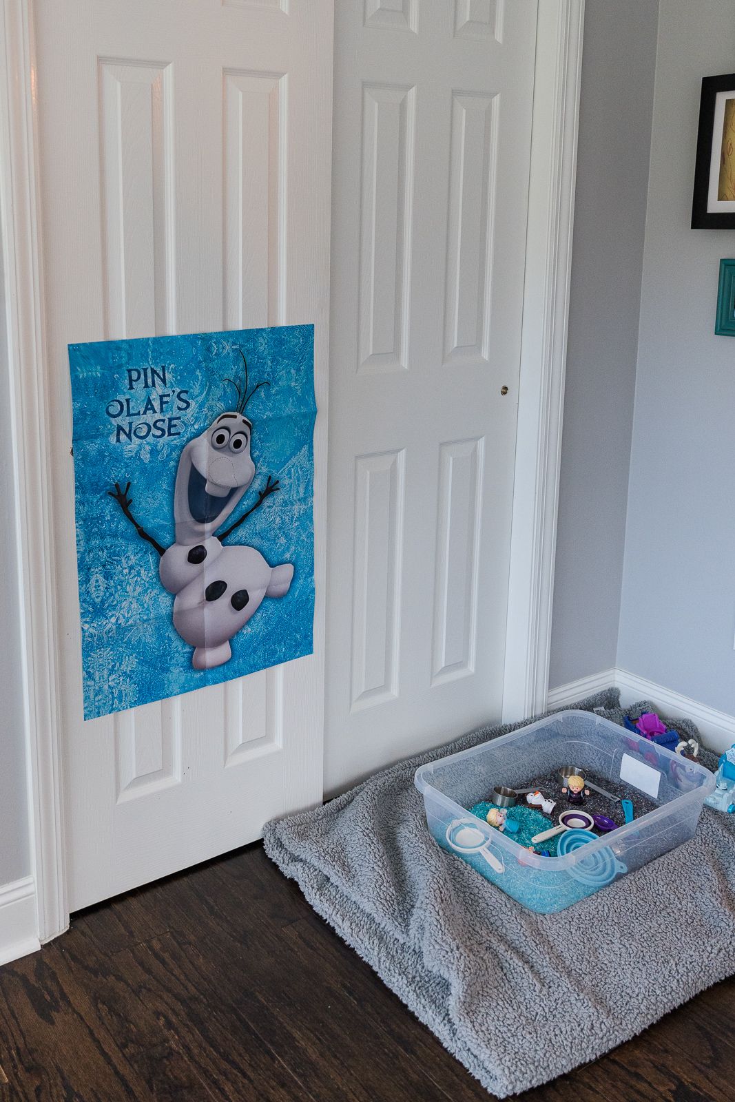 Olaf 'Pin the Nose' game poster on white door with sensory bin activity below.