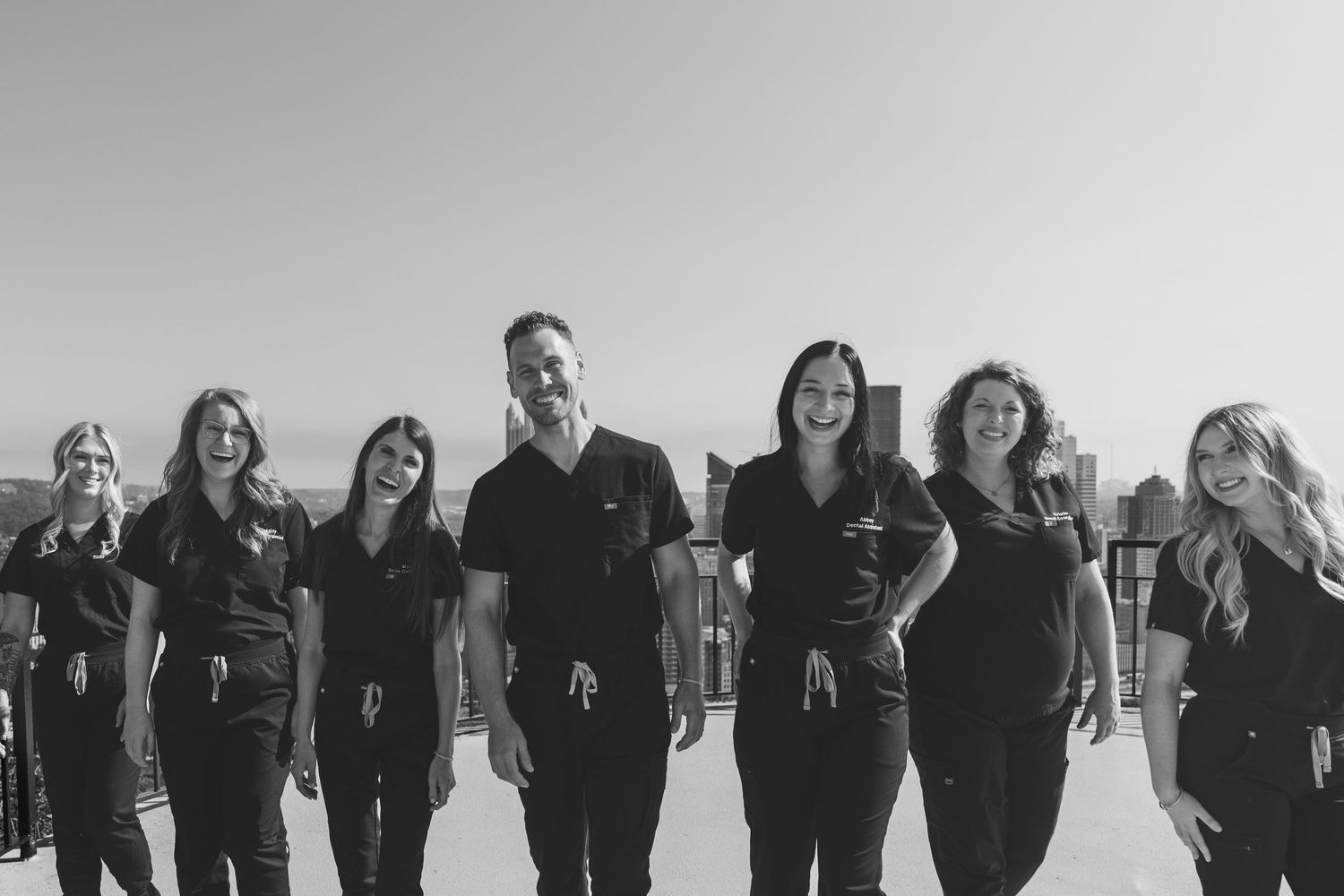 A group of people wearing black outfits walk together outdoors in a black and white photograph.