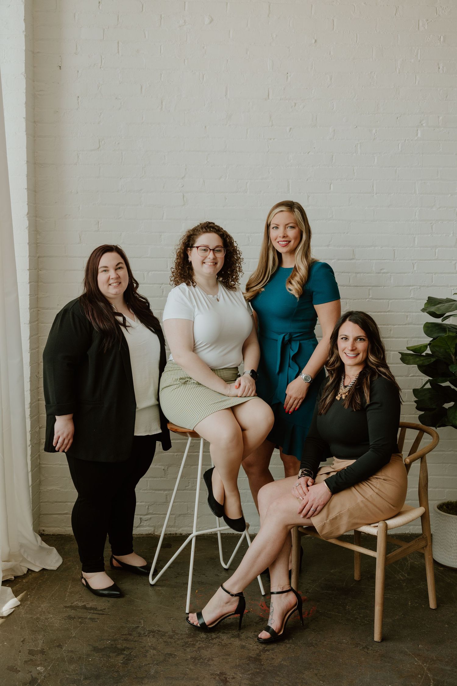 A group of people sitting together on chairs against a white brick wall in a casual studio setting.