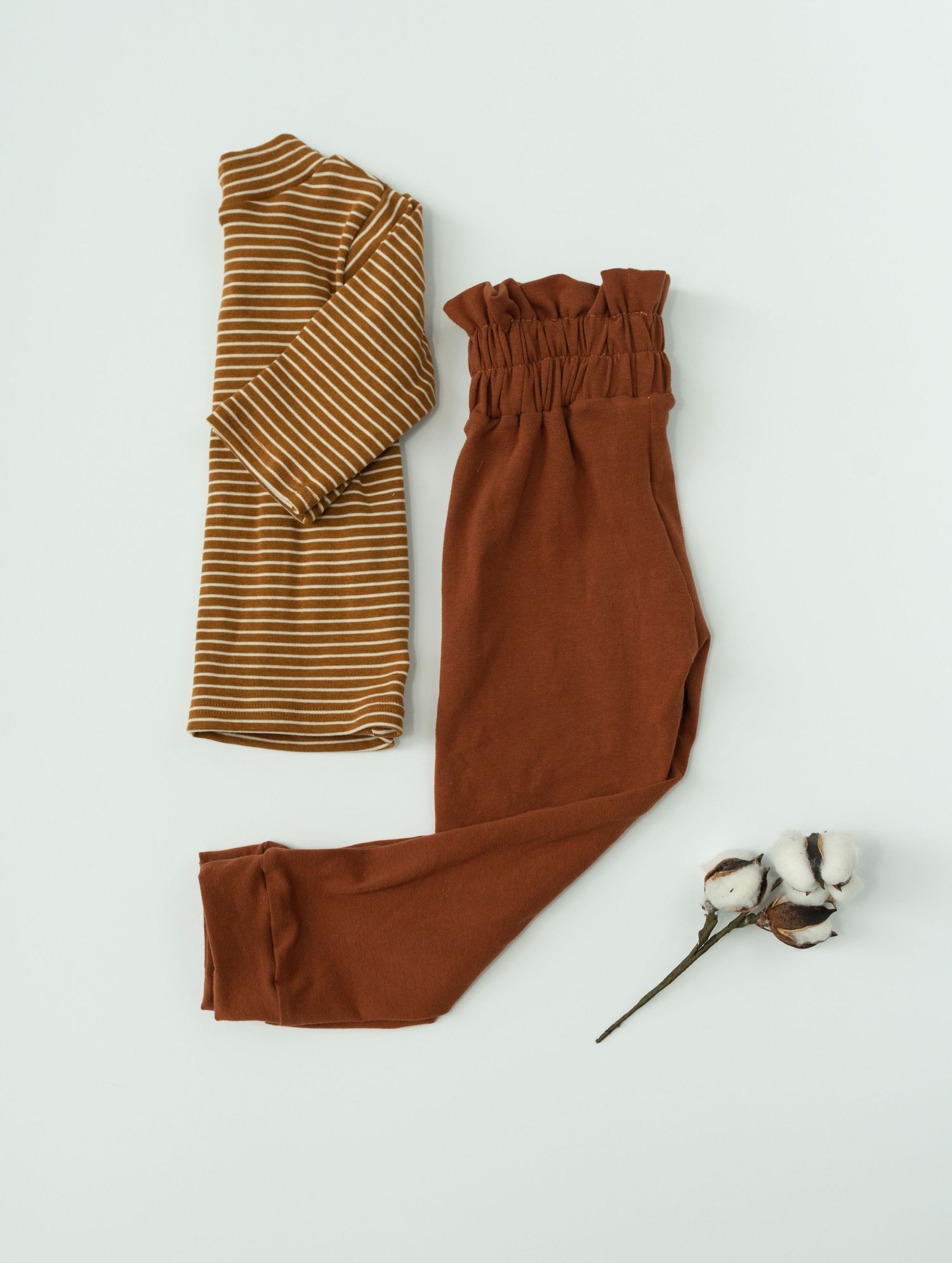 Flat lay sequence of folding brown and striped clothing items with cotton stems on white background.