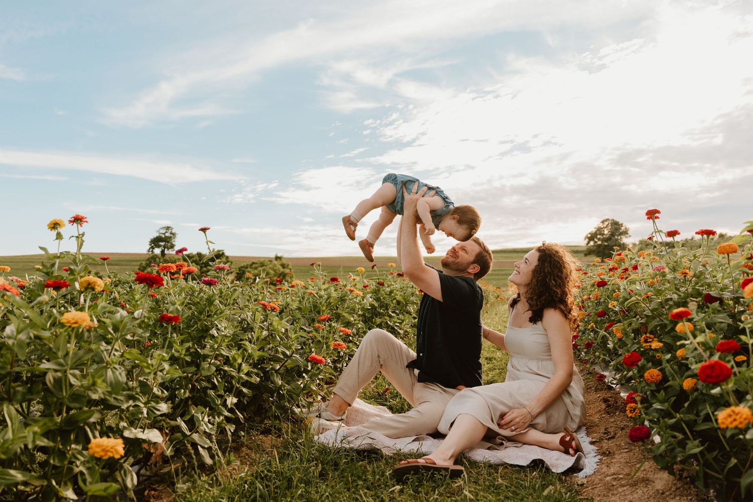 Family enjoying picnic in sunflower field during golden hour.