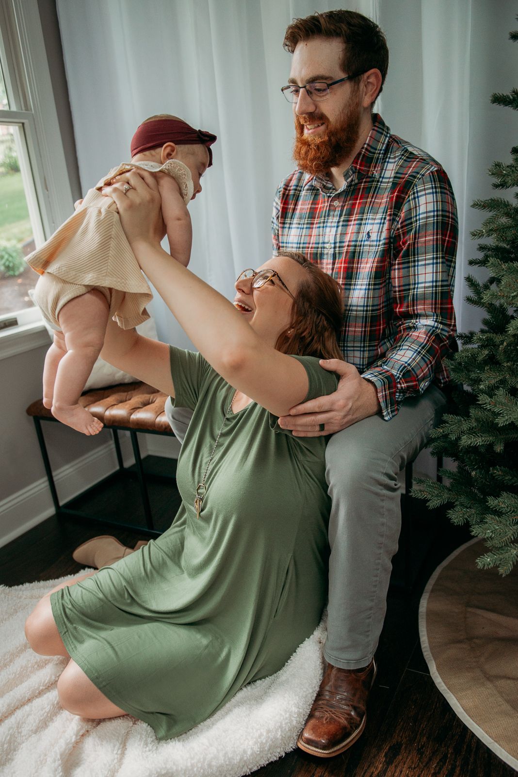 A family shares a playful moment together near a decorated Christmas tree.