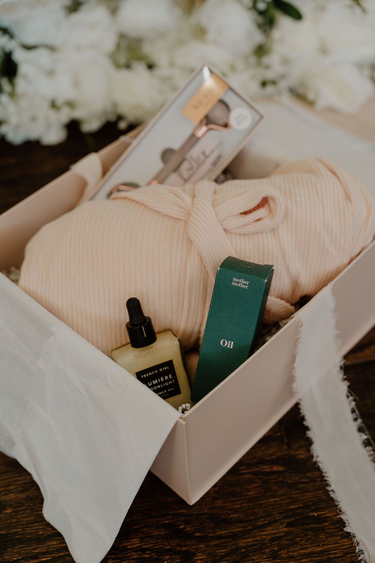White gift boxes with green perfume bottles nestled in cotton on a rustic wooden surface.