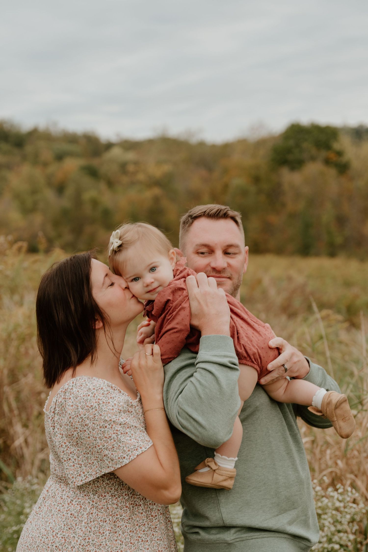 A loving family embraces and shares joyful moments together in a scenic autumn field at sunset.