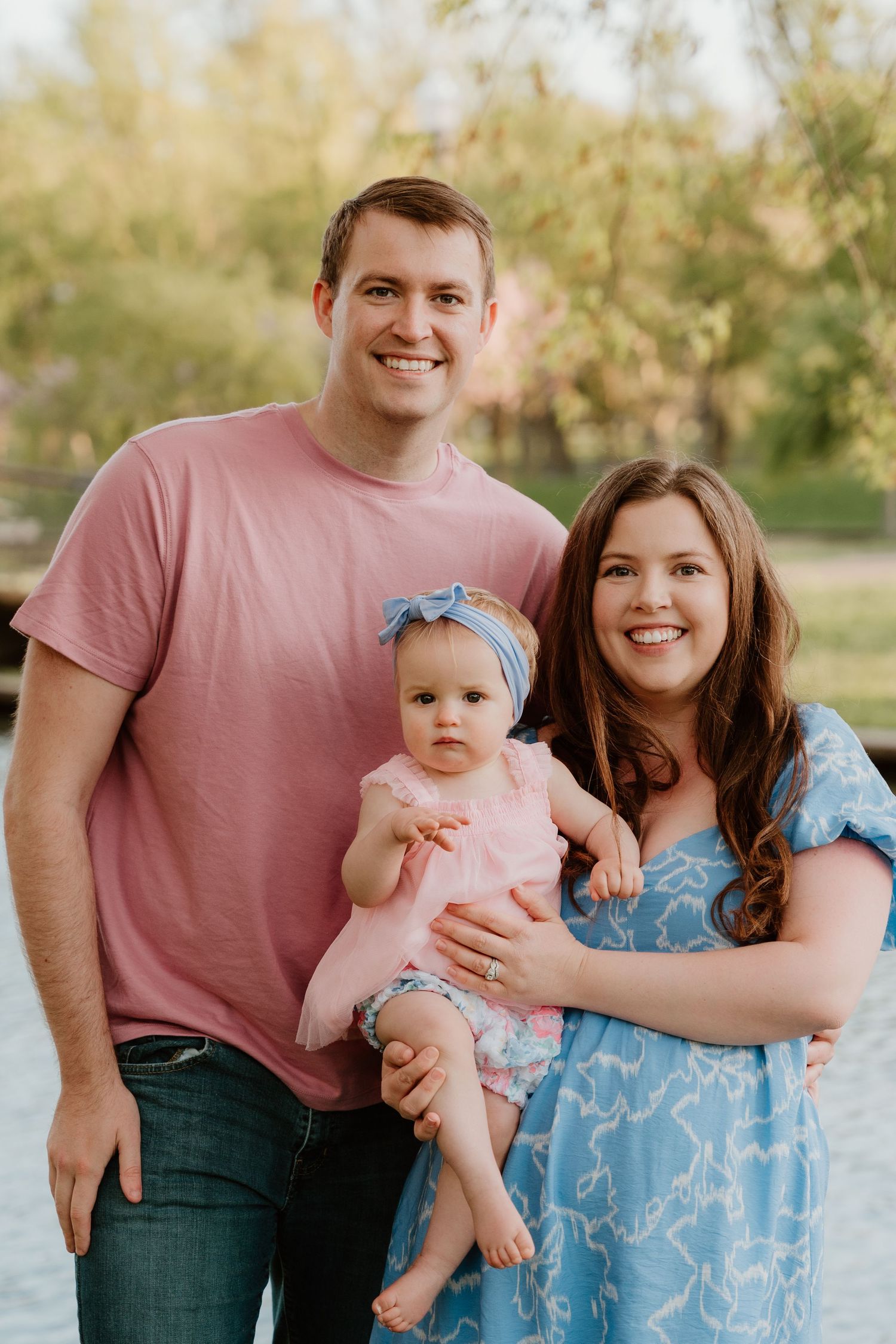 Family portrait in spring park with lake and trees in background.