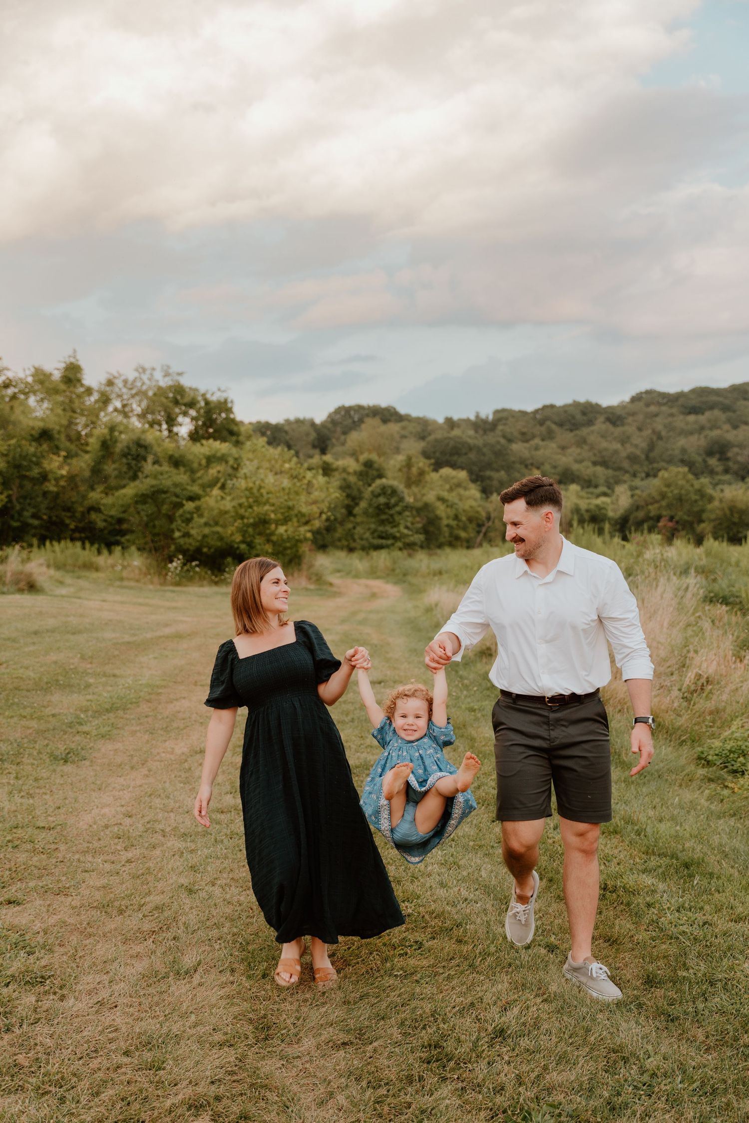 A family plays together in a grassy field on a cloudy day, creating a sequence of joyful movements and interactions.