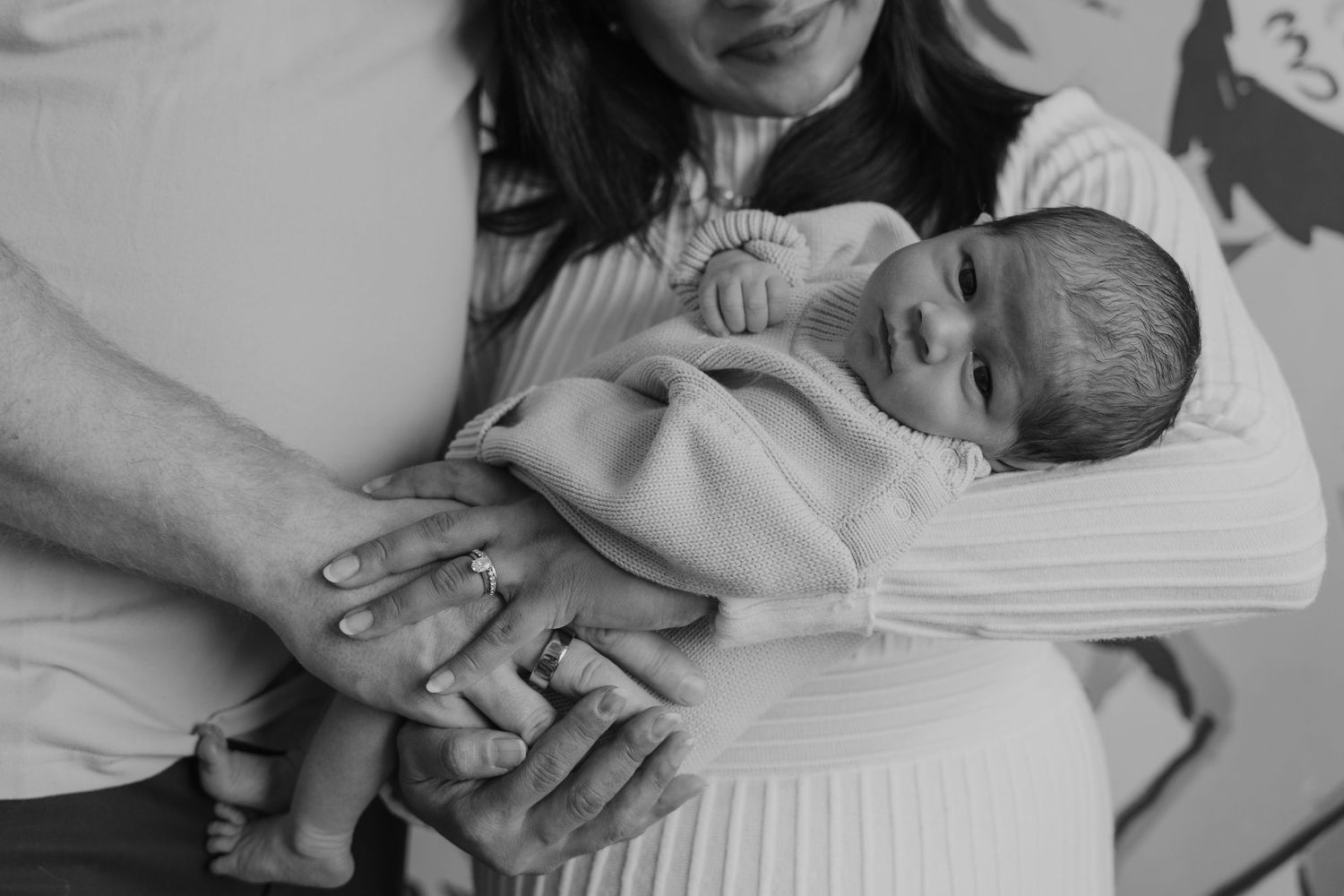 A series of black and white photos showing tender moments between parents and newborn babies in a hospital setting.