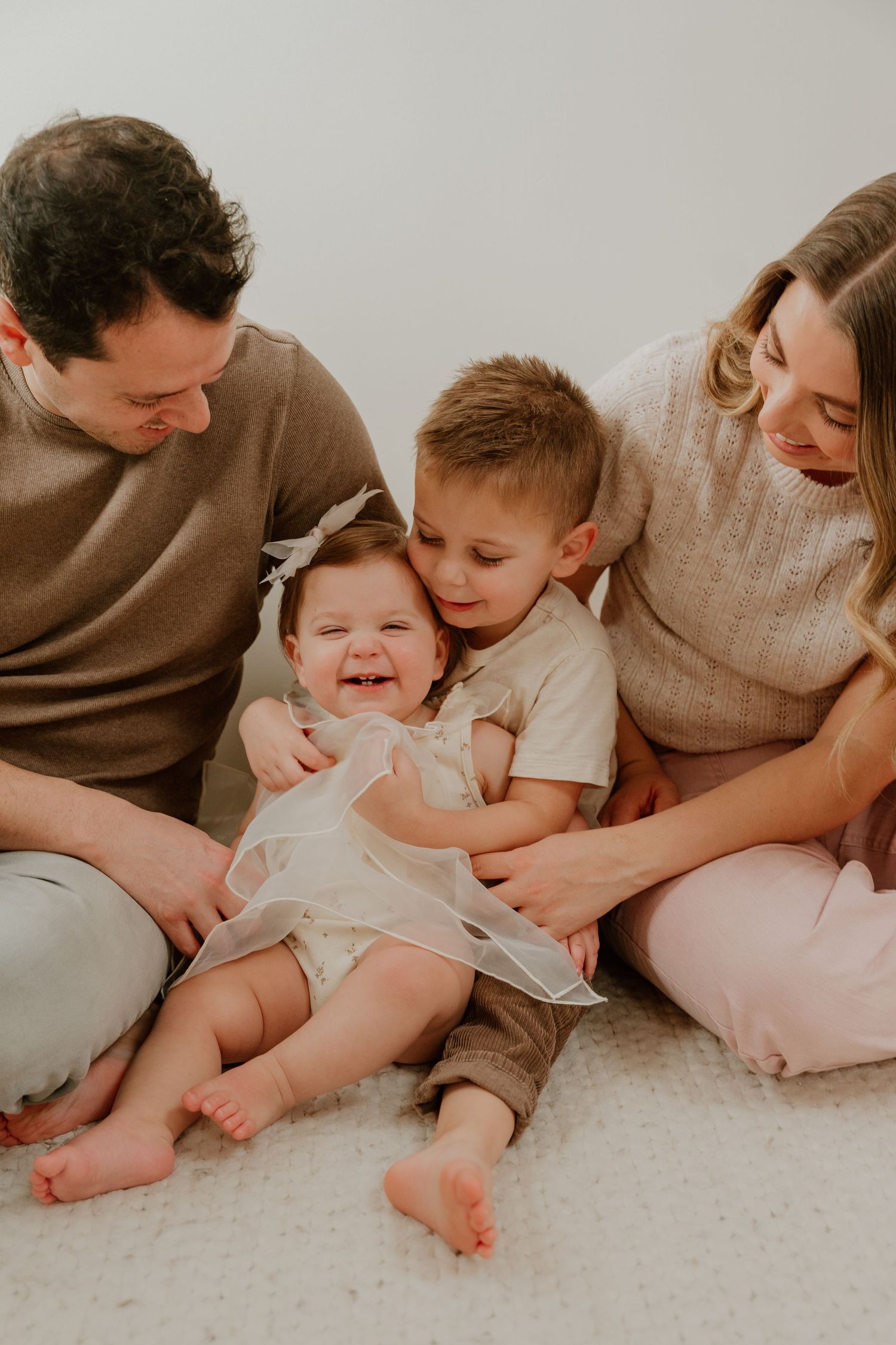 A heartwarming sequence of family photos showing parents cuddling with their baby on a light carpet.