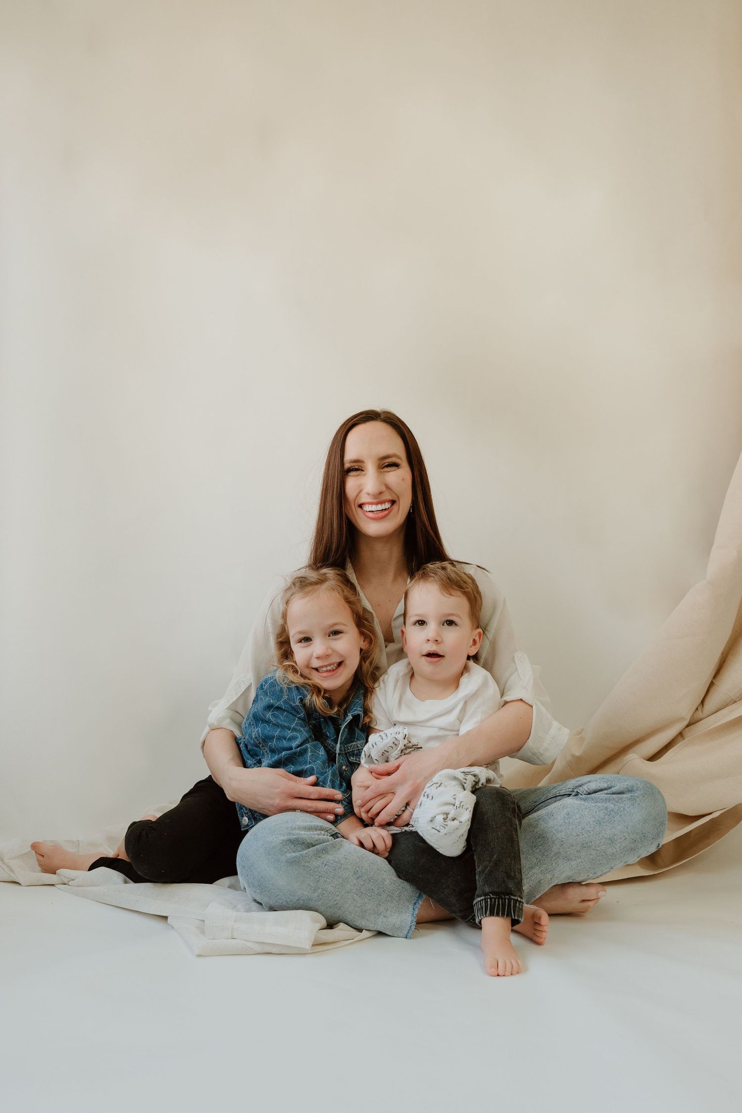 Natural studio portrait against cream backdrop with soft lighting.