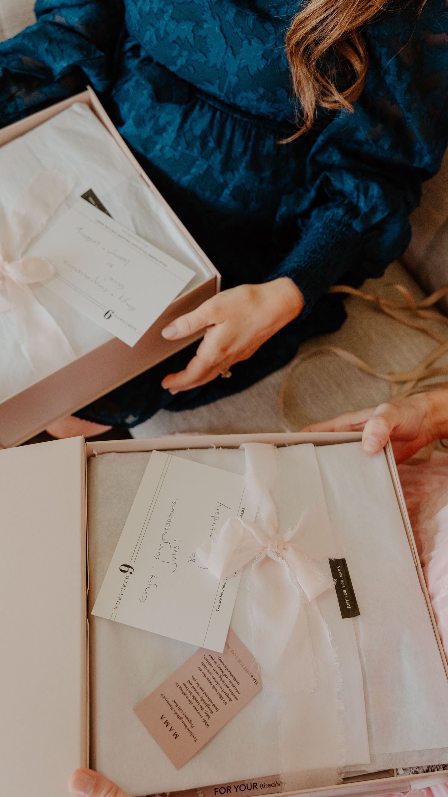Hands delicately unwrap tissue paper from a package, revealing white paper documents inside.