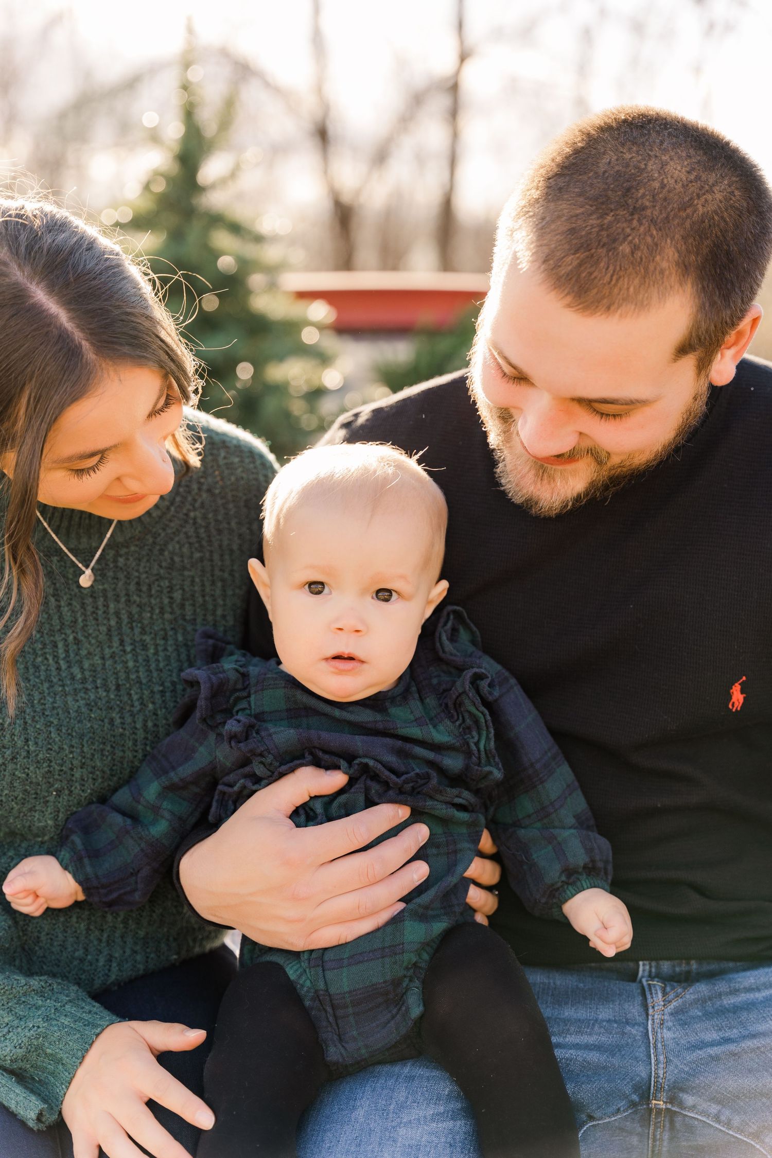 Family of three sharing intimate moment outdoors in warm sunset light.
