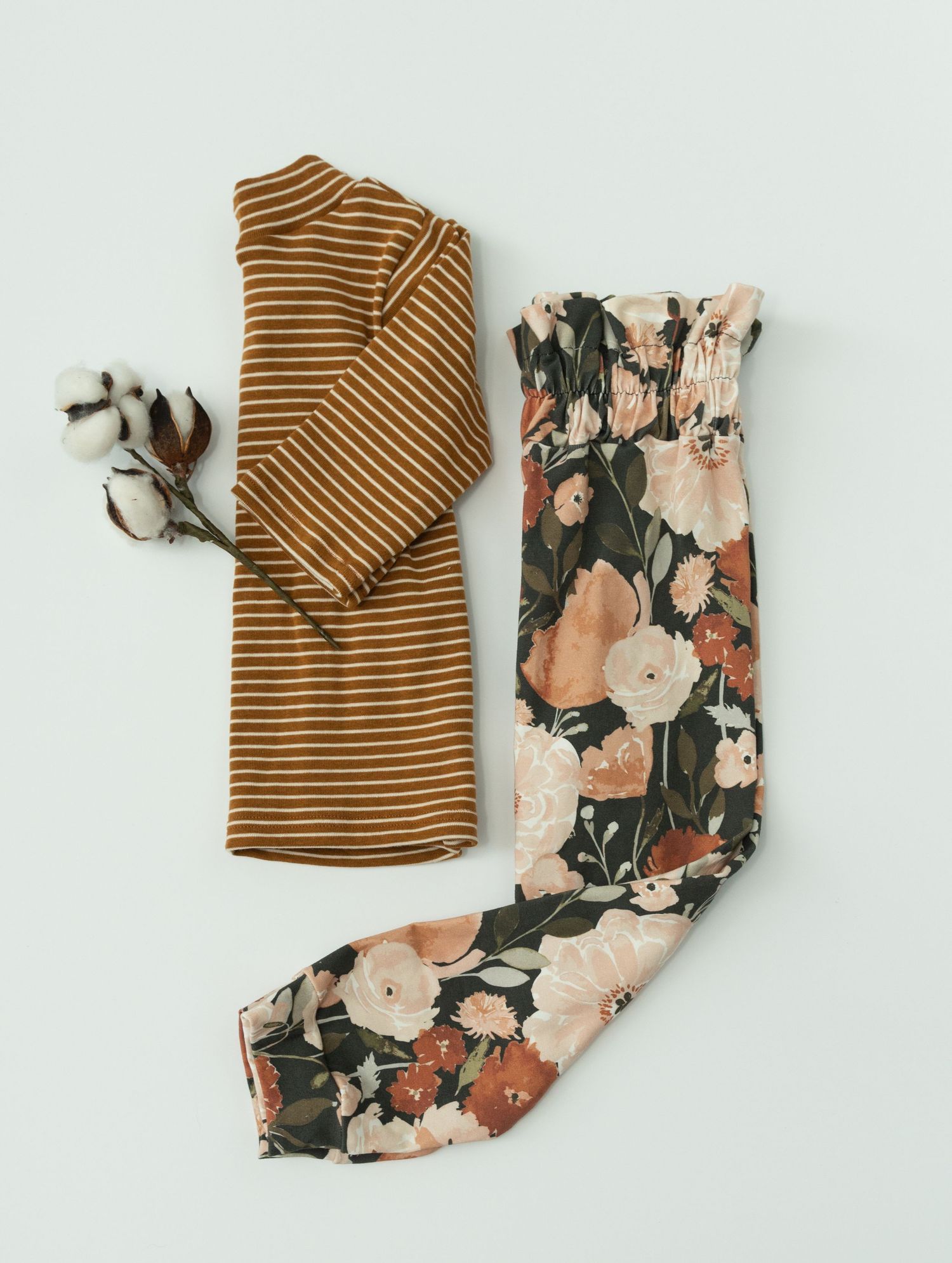 Brown striped shirt and floral pants laid flat in various folded positions against white background.