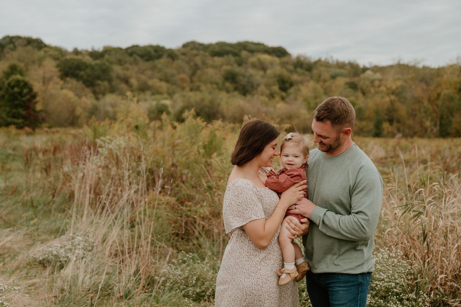 Candid family moments captured in outdoor setting with natural lighting and rustic backdrop.