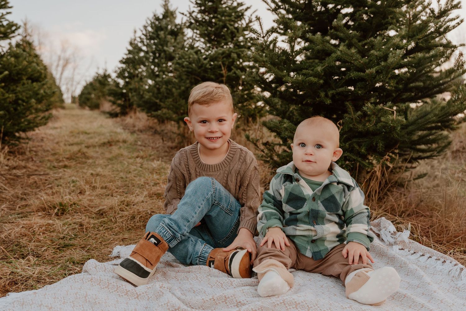 A family in coordinating blue outfits sits together in a grassy outdoor setting during an autumn photo session.